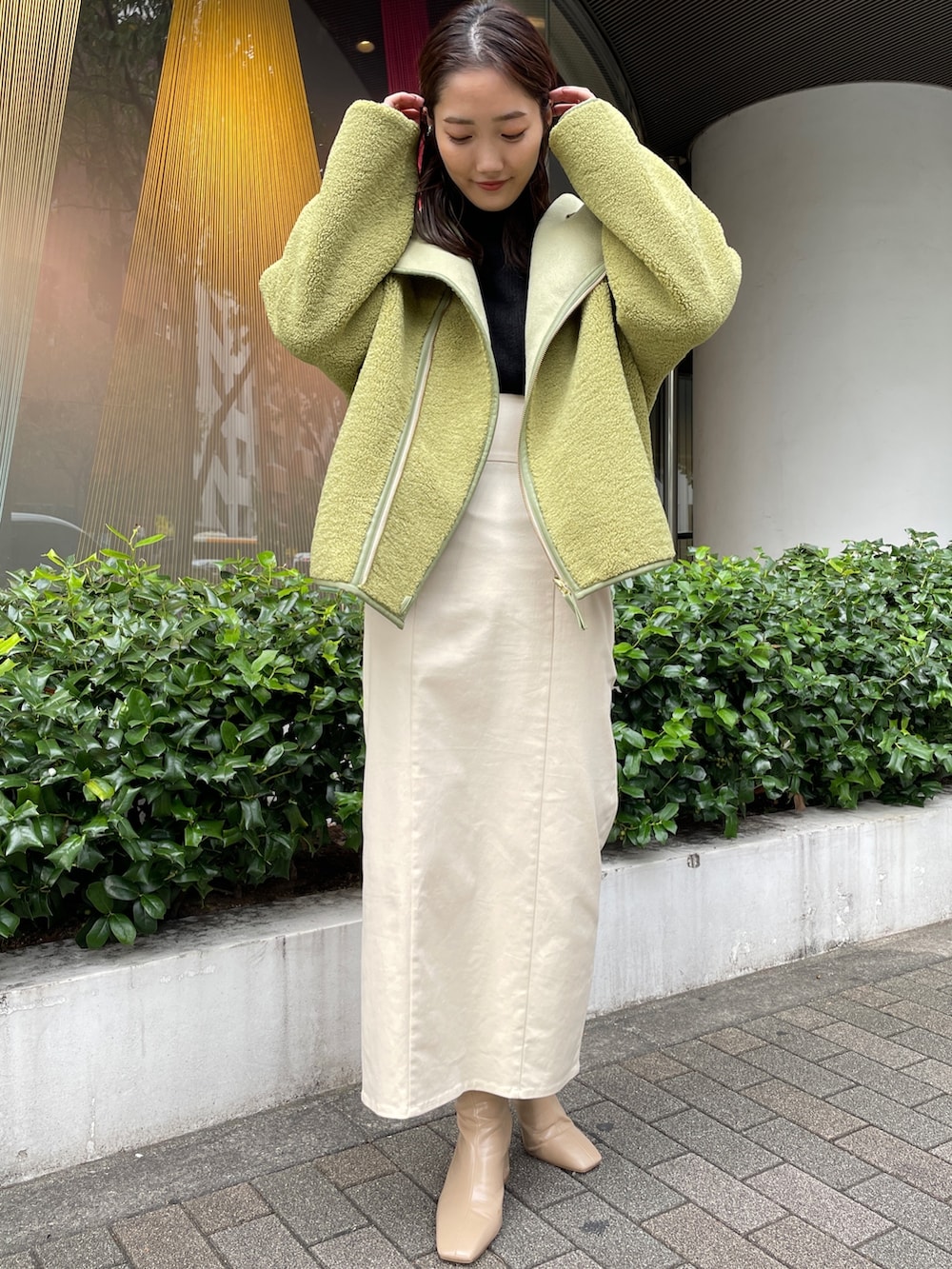 ベージュ系のブーツ、ブラック系のニット/セーター、ホワイト系のスカートを着用したレディースの秋コーディネートの2枚目の写真