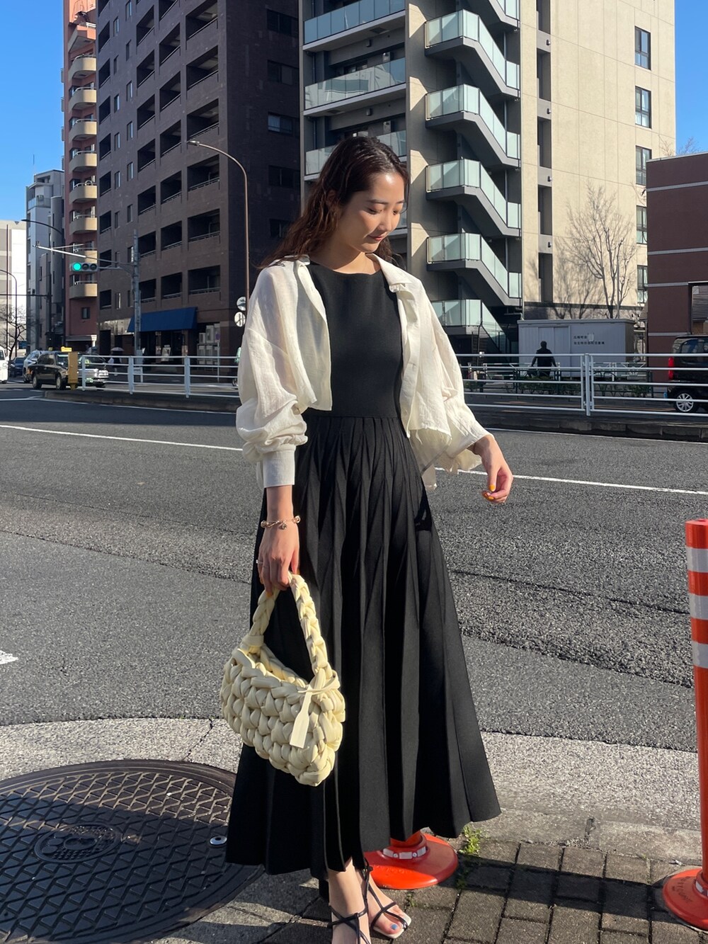 ブラック系のワンピース、ベージュ系のハンドバッグ、ブラック系のサンダルを着用したレディースの春コーディネートの2枚目の写真