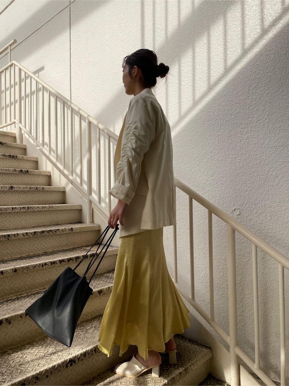 ホワイト系のシャツ/ブラウス、ホワイト系のテーラードジャケット、イエロー系のスカートを着用したレディースの冬コーディネートの2枚目の写真