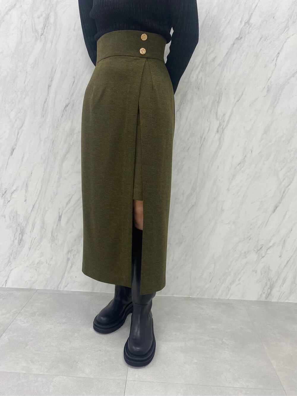 ベージュ系のスカート、ブラック系のニット/セーター、ブラック系のブーツを着用したレディースの夏コーディネートの10枚目の写真