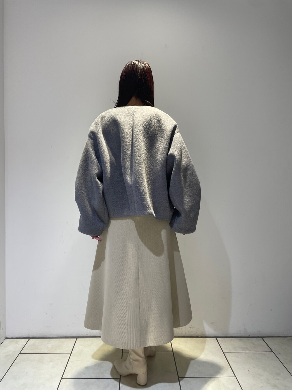 グレー系のブルゾン、ホワイト系のブーツ、ホワイト系のジャンパースカートを着用したレディースの秋コーディネートの5枚目の写真