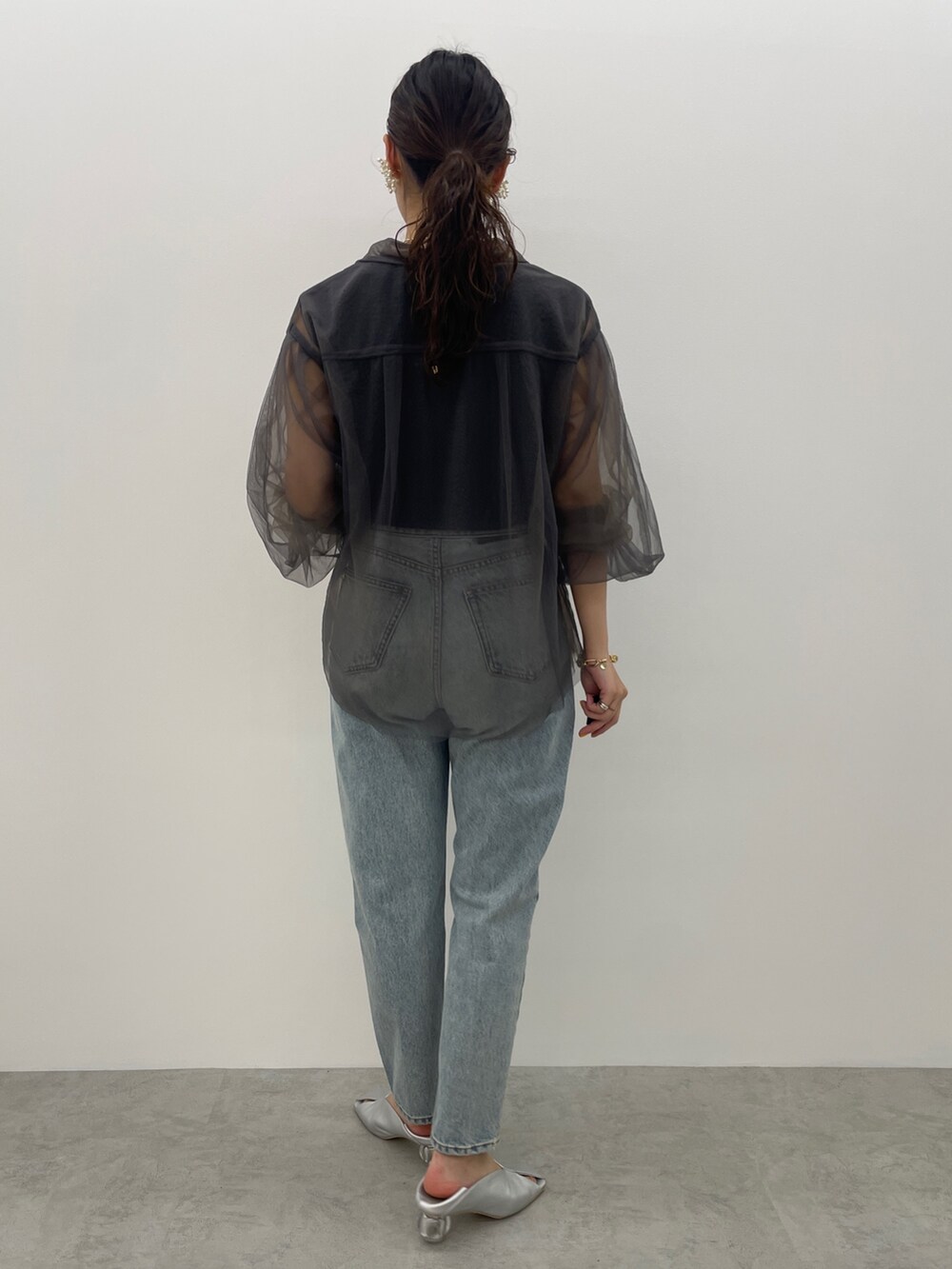 ブルー系のデニムパンツ、シルバー系のパンプス、ブラック系のニット/セーターを着用したレディースの夏コーディネートの5枚目の写真