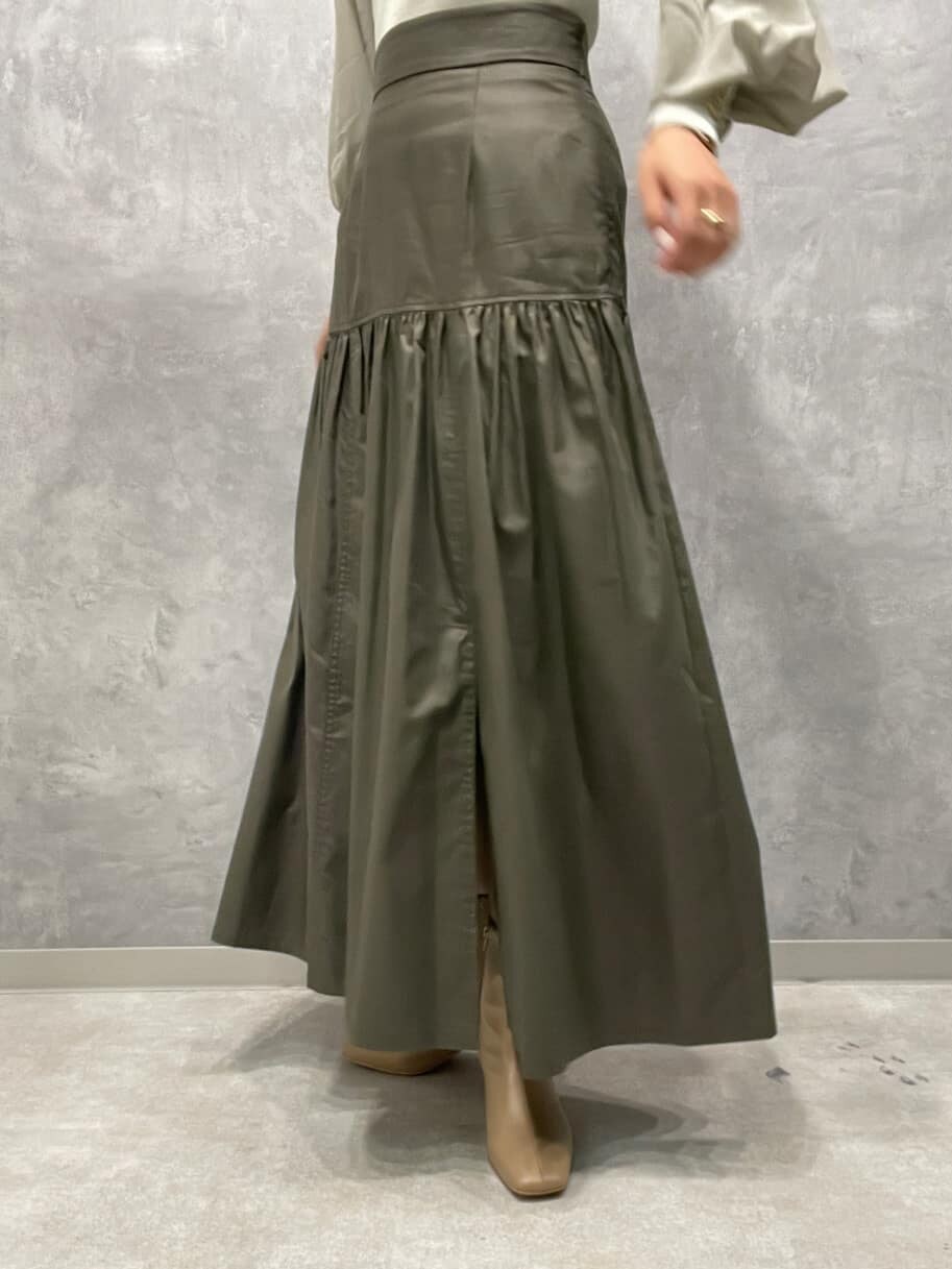 ベージュ系のスカート、ベージュ系のブーツ、グリーン系のニット/セーターを着用したレディースの夏コーディネートの9枚目の写真