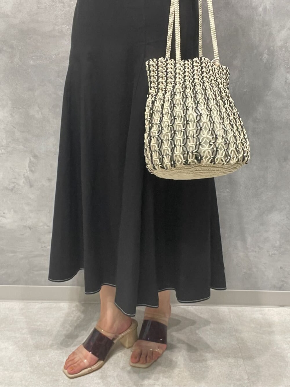 ブラウン系のサンダル、ホワイト系のハンドバッグ、ブラック系のワンピースを着用したレディースの夏コーディネートの10枚目の写真