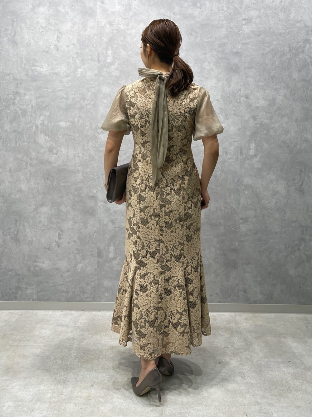 ベージュ系のドレス、シルバー系のパンプス、シルバー系のクラッチバッグを着用したレディースの夏コーディネートの4枚目の写真