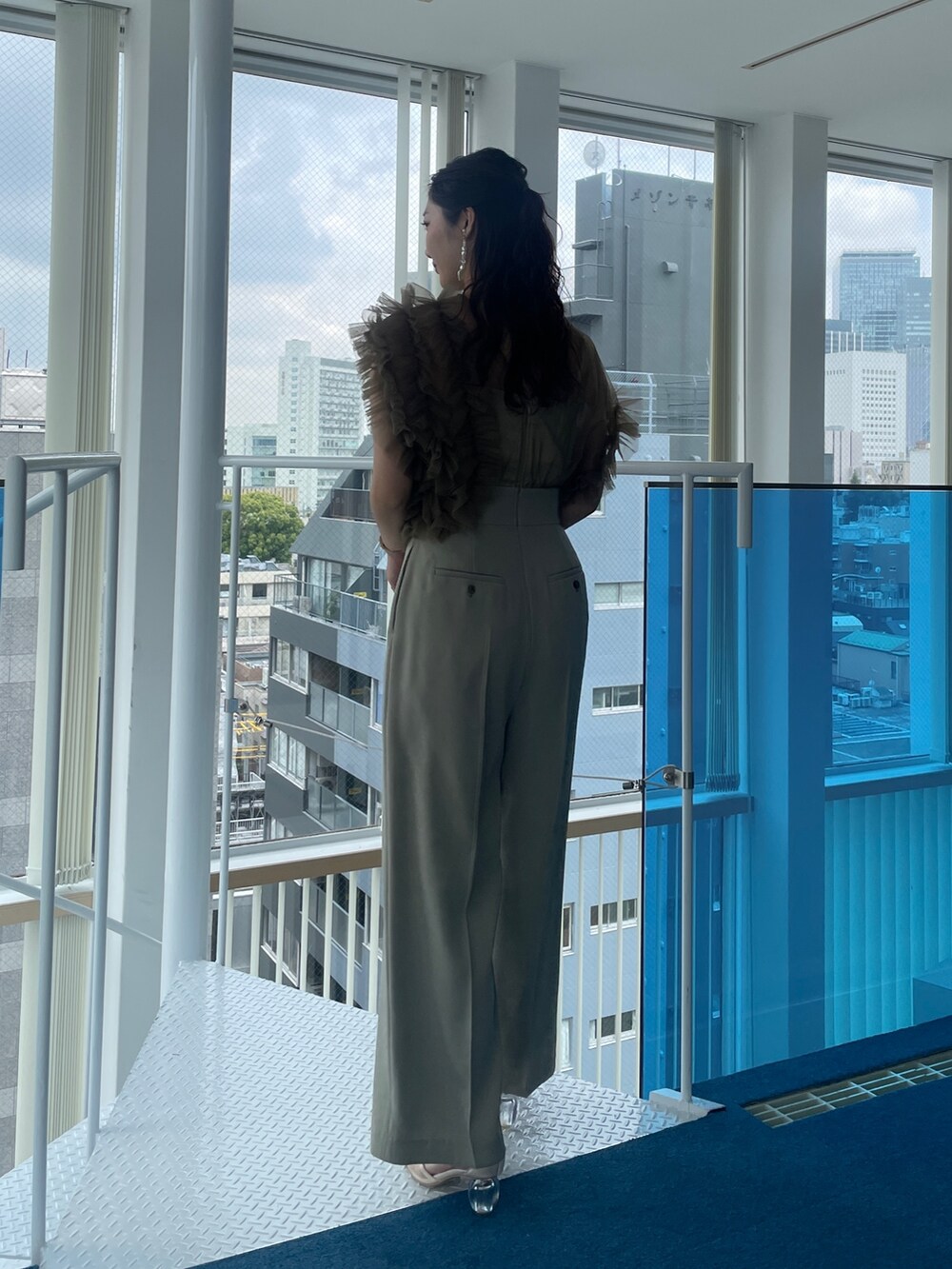 グリーン系のパンツドレス、ベージュ系のパンプスを着用したレディースの春コーディネートの4枚目の写真