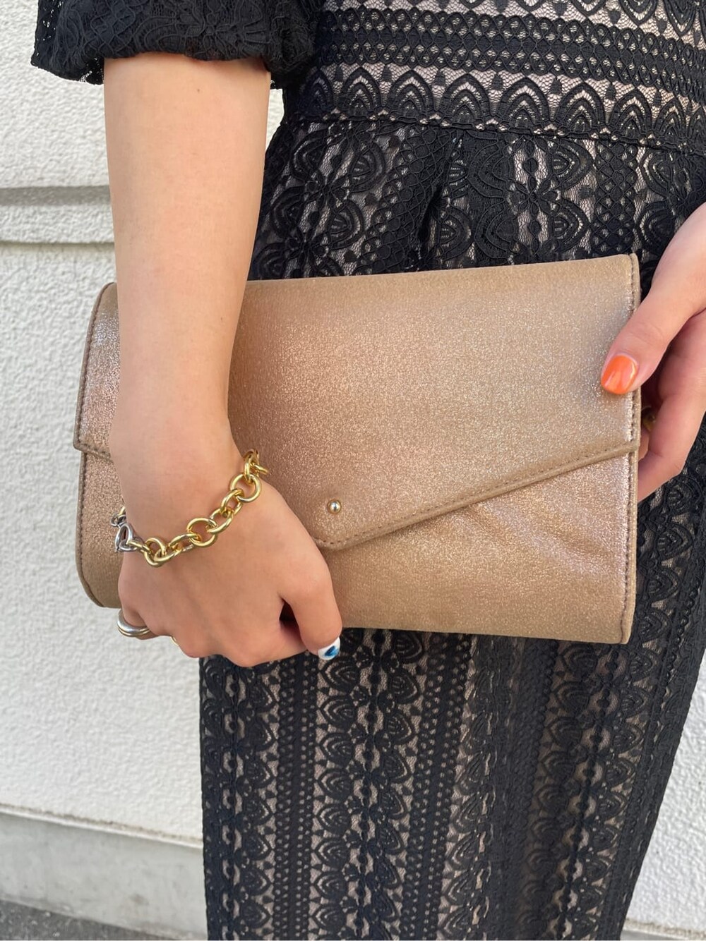 ゴールド系のパンプス、ゴールド系のクラッチバッグ、ブラック系のドレスを着用したレディースの冬コーディネートの9枚目の写真