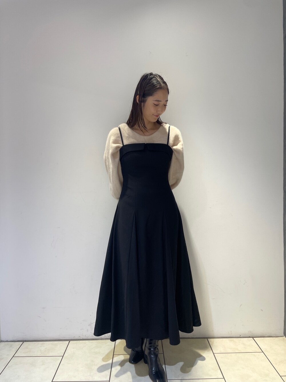 ホワイト系のニット/セーター、ブラック系のワンピース、ブラック系のブーツを着用したレディースの秋コーディネートの4枚目の写真