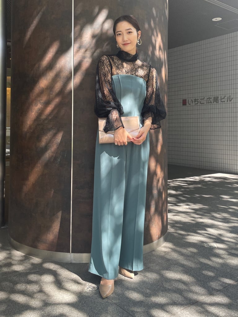 ゴールド系のクラッチバッグ、ゴールド系のパンプス、ブラック系のシャツ/ブラウスを着用したレディースの秋コーディネートの3枚目の写真