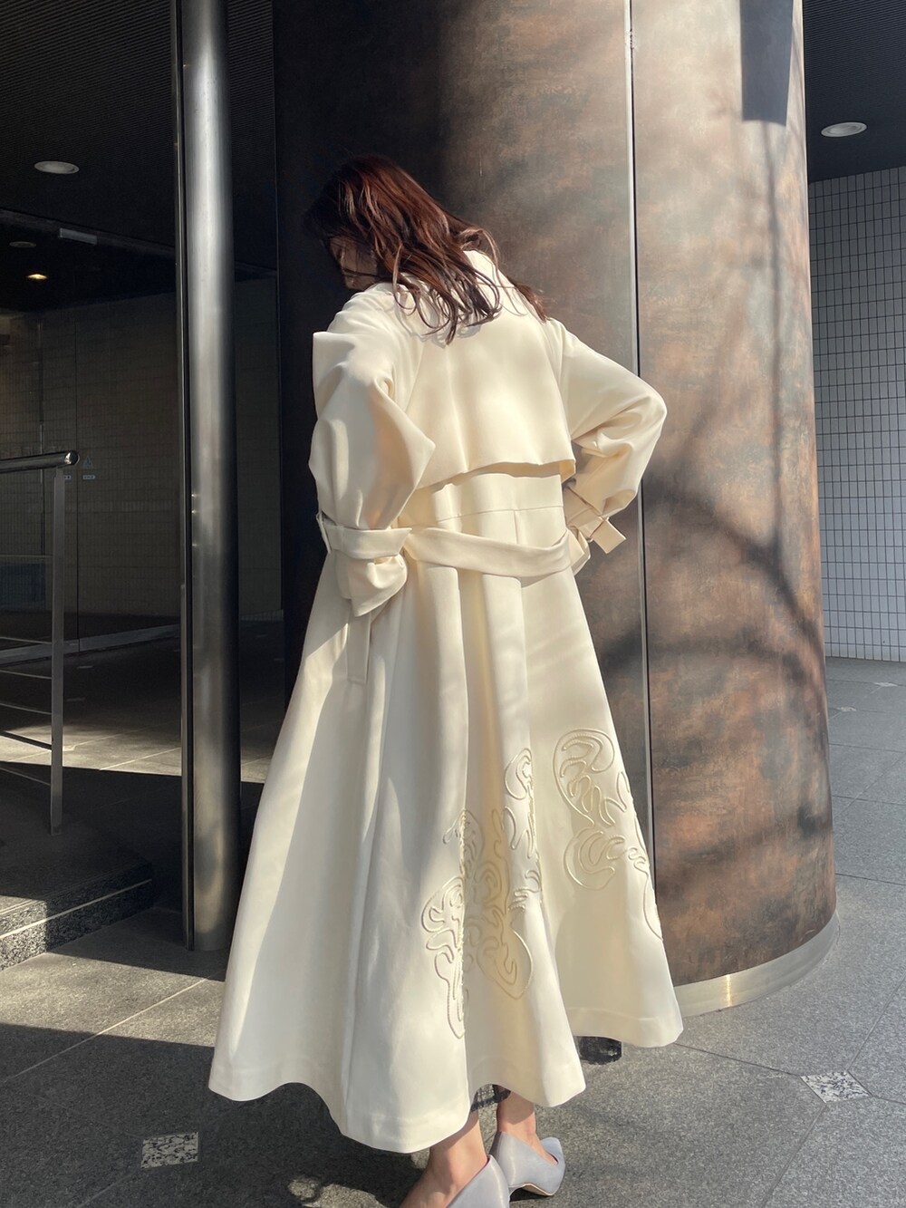 グレー系のドレス、グレー系のパンプス、ホワイト系のトレンチコートを着用したレディースの冬コーディネートの3枚目の写真