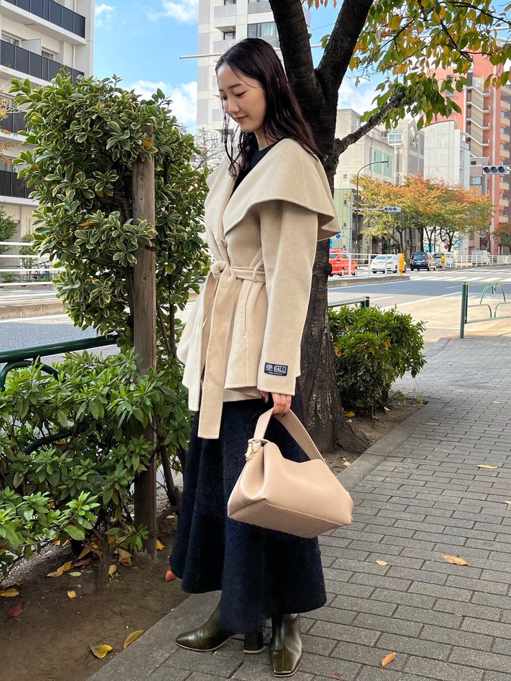 ブラック系のスカート、ブラック系のニット/セーター、グリーン系のブーツを着用したレディースの秋コーディネートの4枚目の写真