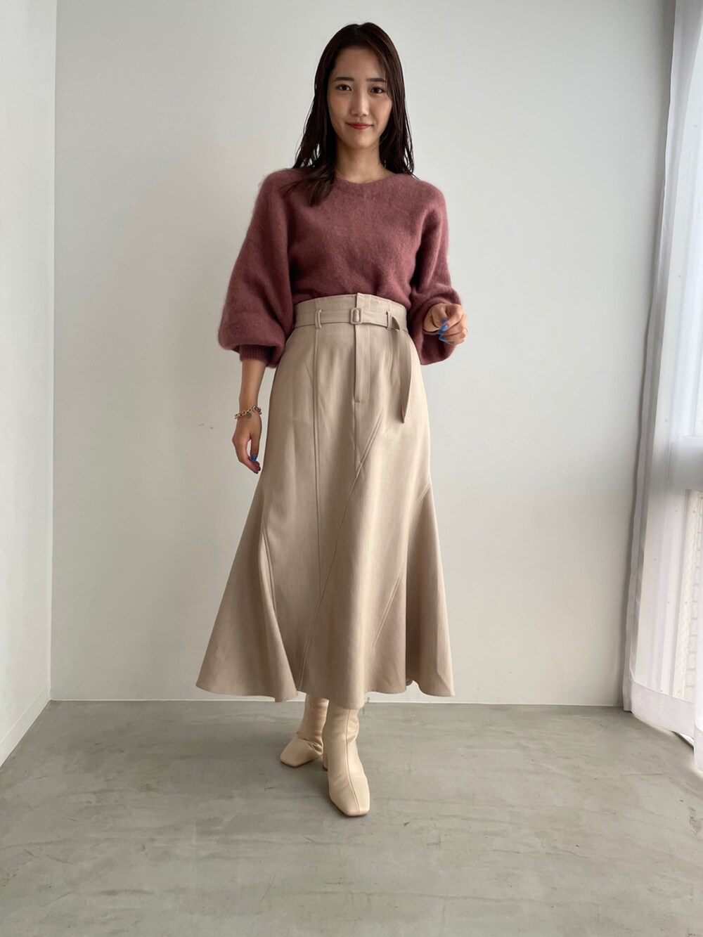 ホワイト系のブーツ、ベージュ系のスカート、ピンク系のニット/セーターを着用したレディースの夏コーディネートの2枚目の写真