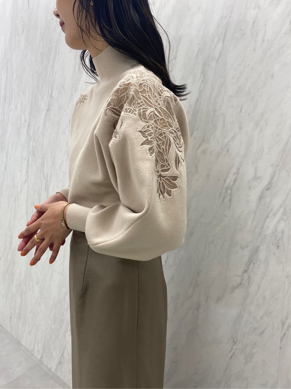 ブラック系のブーツ、ベージュ系のスカート、ホワイト系のニット/セーターを着用したレディースの秋コーディネートの7枚目の写真