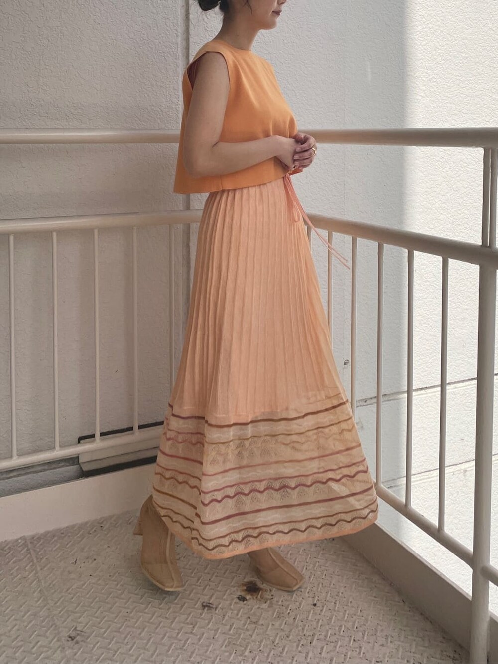 ベージュ系のブーツ、ベージュ系のテーラードジャケット、オレンジ系のワンピースを着用したレディースの春コーディネートの4枚目の写真