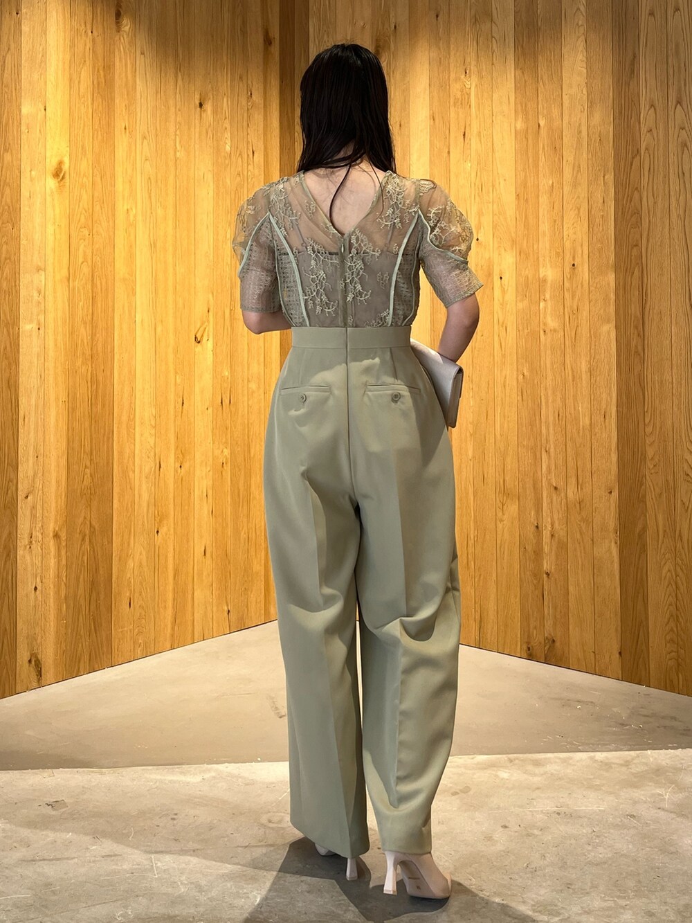 ベージュ系のパンプス、ベージュ系のクラッチバッグ、グリーン系のパンツドレスを着用したレディースの冬コーディネートの5枚目の写真