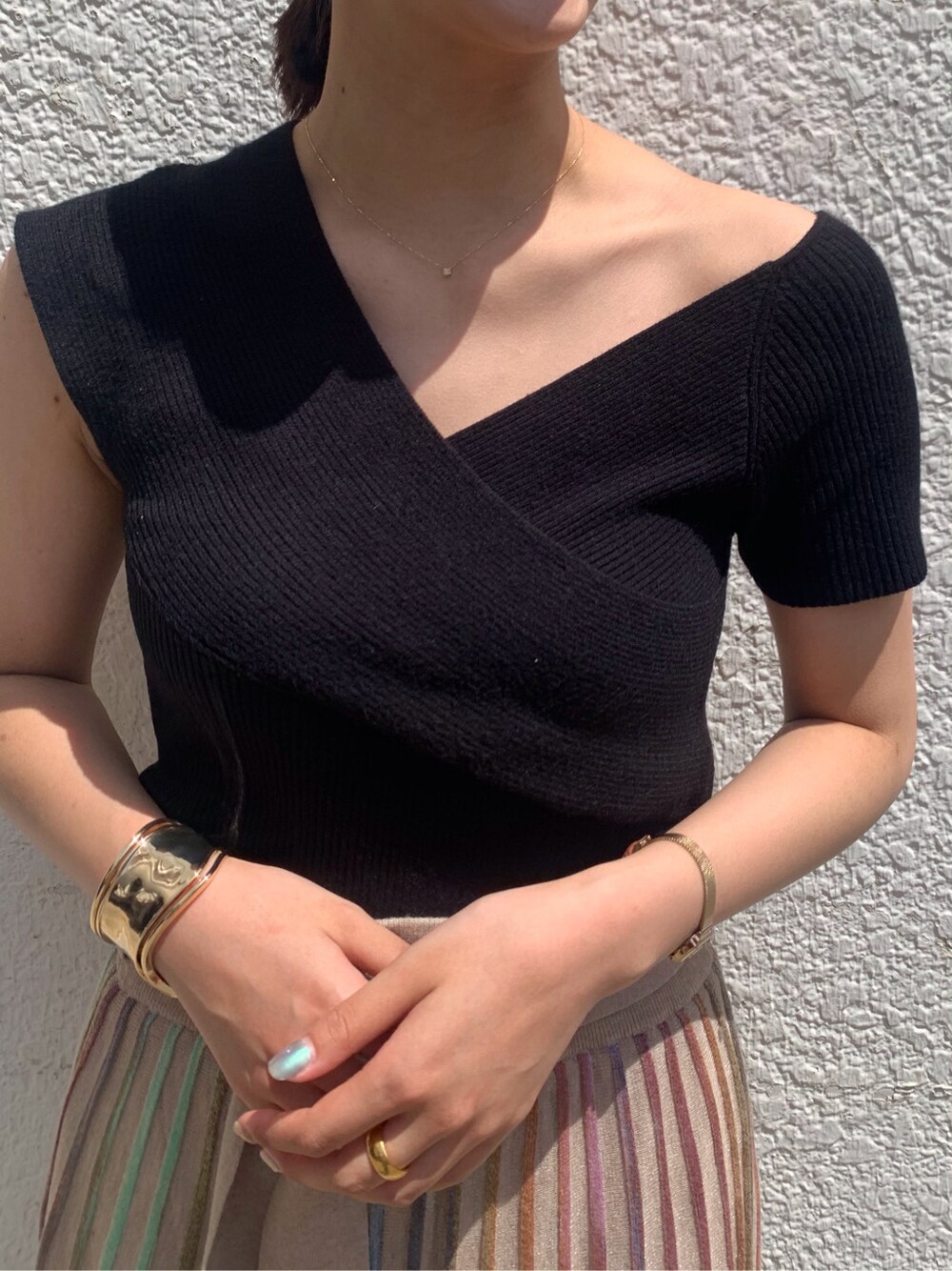 ベージュ系のスカート、ブラック系のニット/セーター、ゴールド系のバングル/リストバンドを着用したレディースの春コーディネートの4枚目の写真