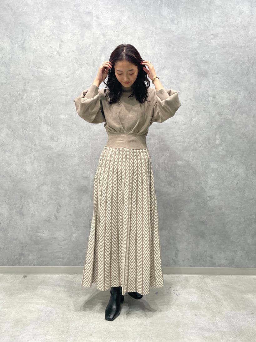 ホワイト系のノーカラーコート、ブラック系のブーツ、ベージュ系のワンピースを着用したレディースの秋コーディネートの3枚目の写真