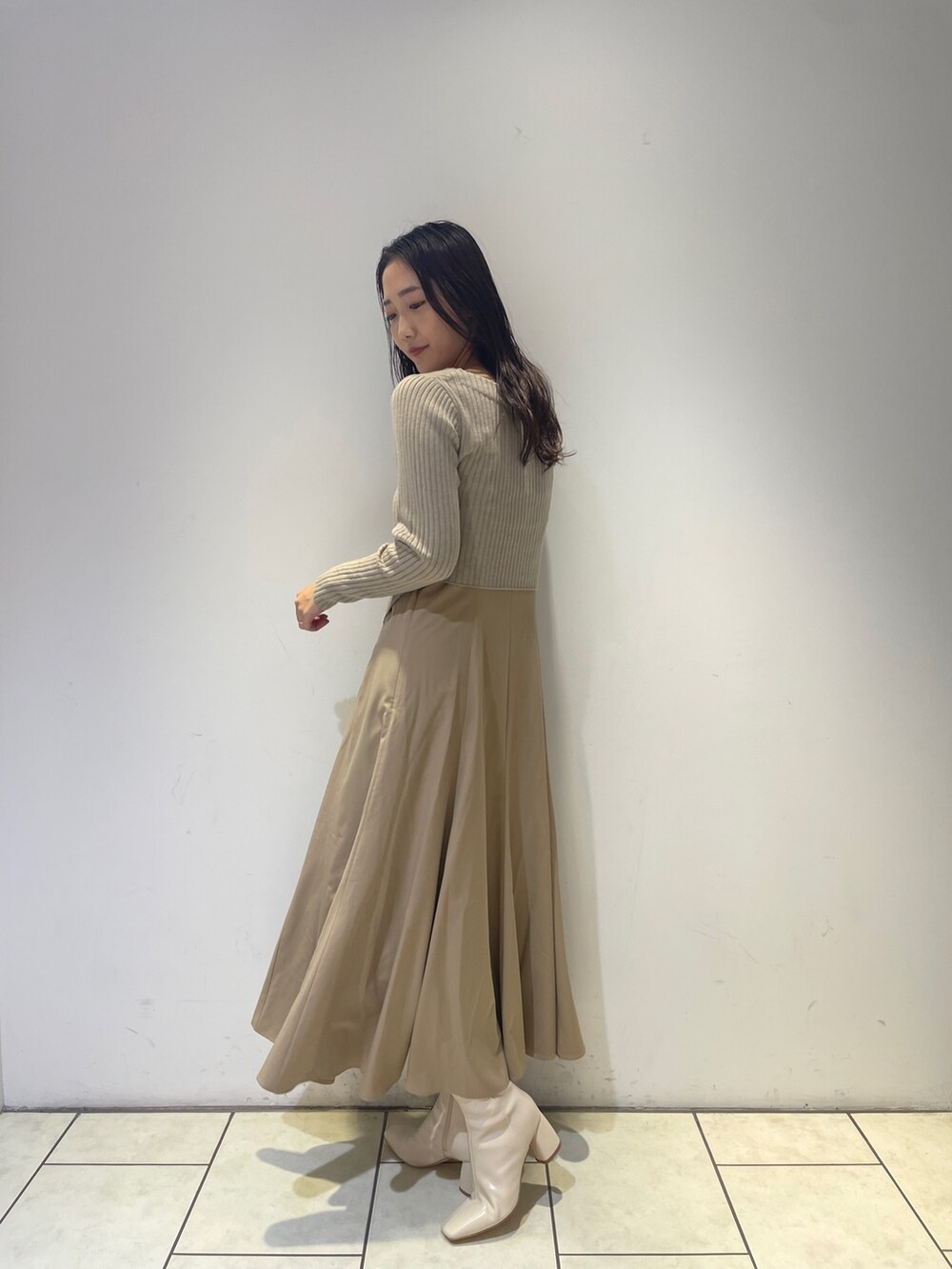 ベージュ系のワンピース、ホワイト系のブーツを着用したレディースの秋コーディネートの4枚目の写真