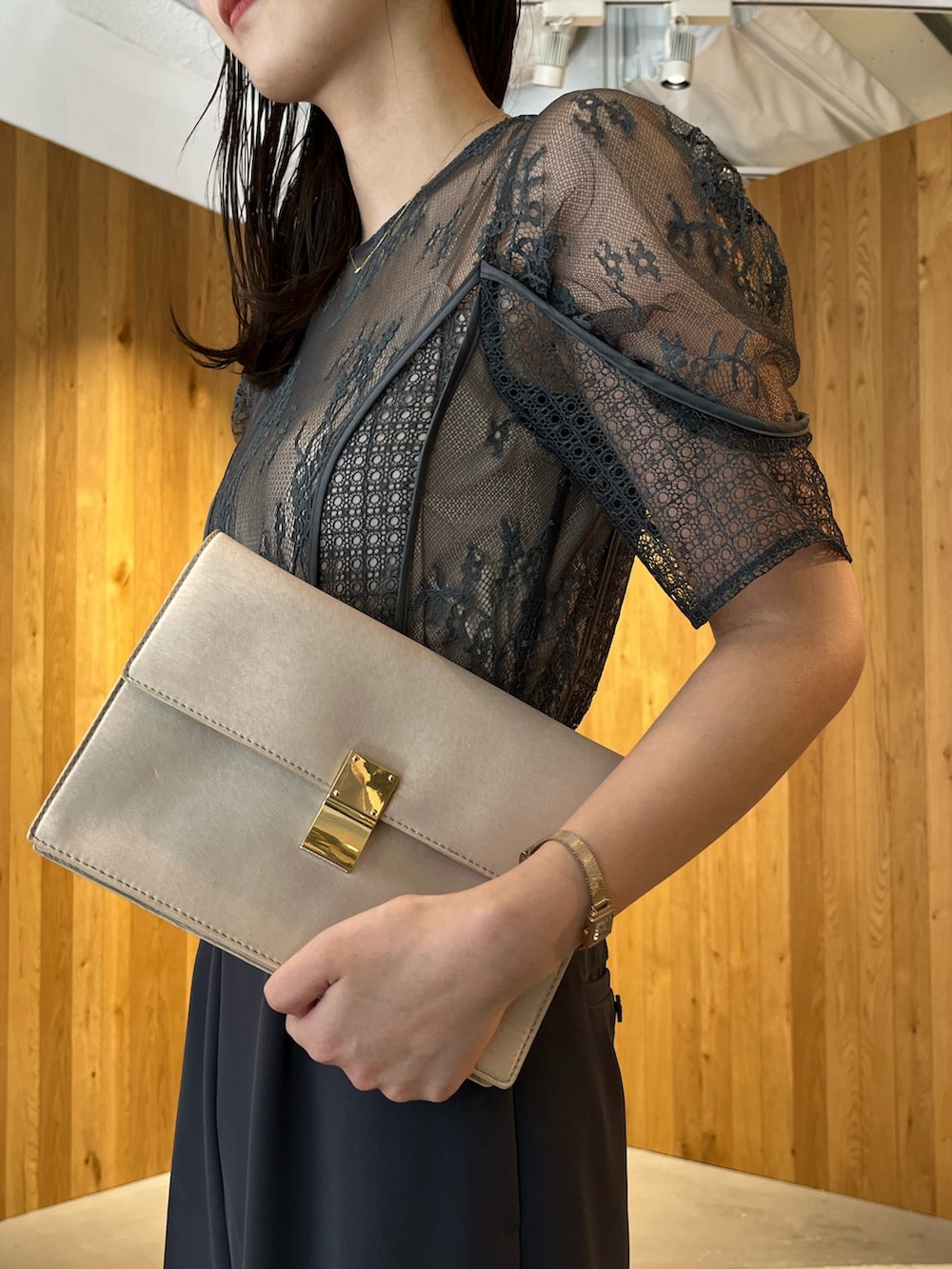 グレー系のパンツドレス、ベージュ系のクラッチバッグ、ベージュ系のパンプスを着用したレディースの冬コーディネートの6枚目の写真