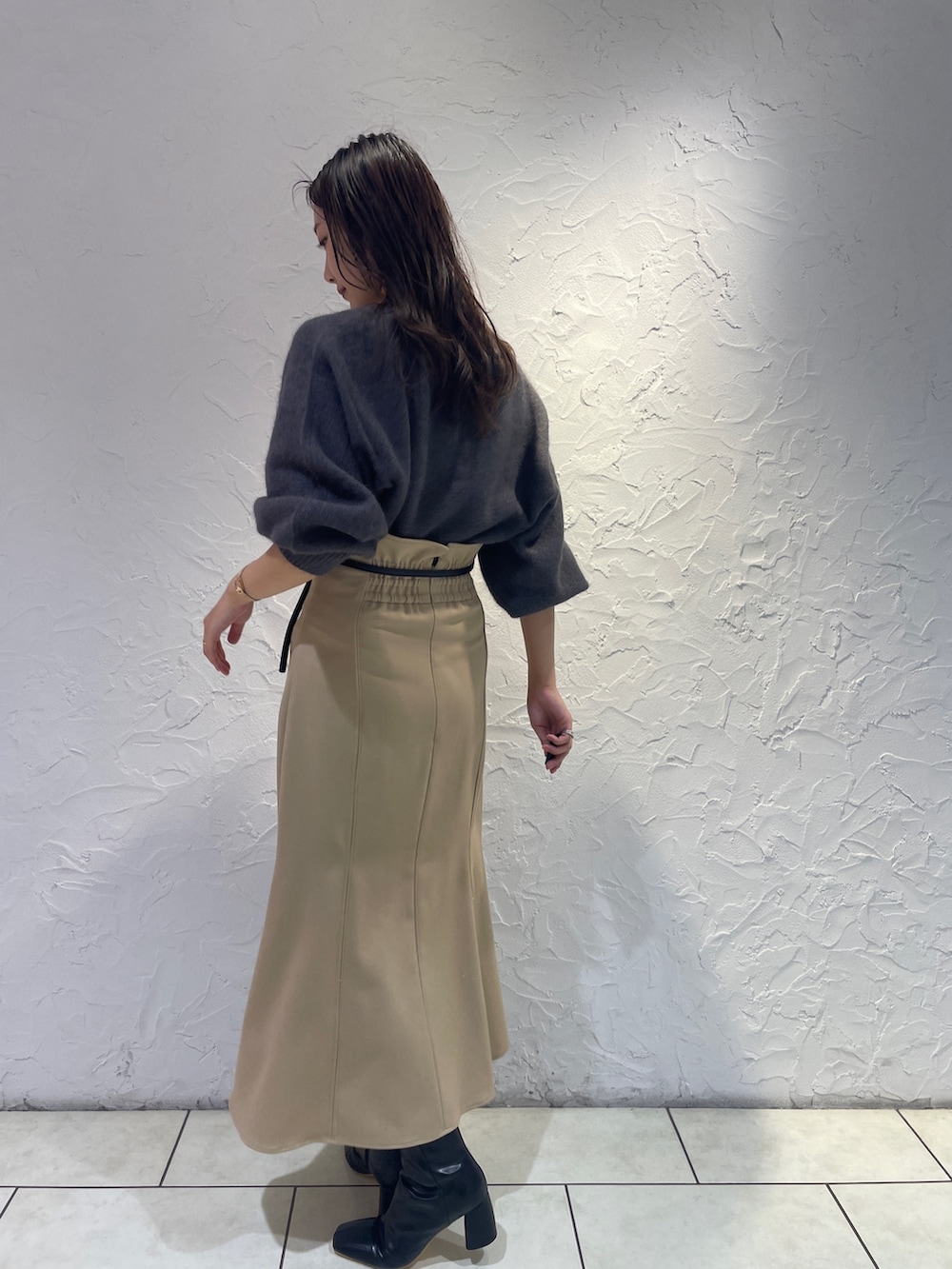 グレー系のニット/セーター、ベージュ系のスカート、ブラック系のブーツを着用したレディースの秋コーディネートの5枚目の写真