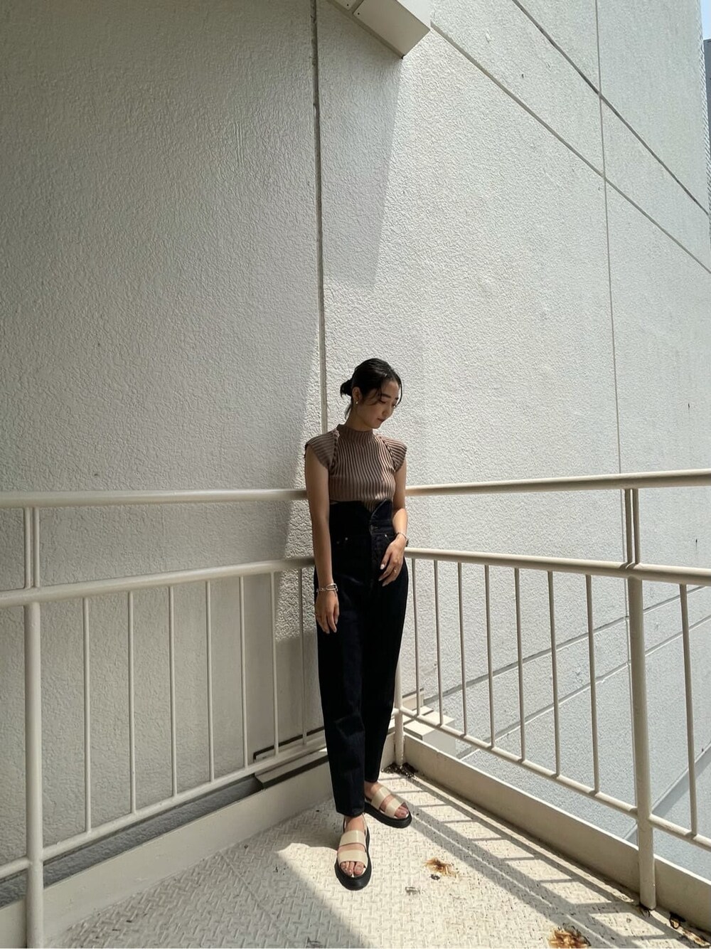 ブルー系のデニムパンツ、ホワイト系のサンダル、ベージュ系のニット/セーターを着用したレディースの夏コーディネートの2枚目の写真