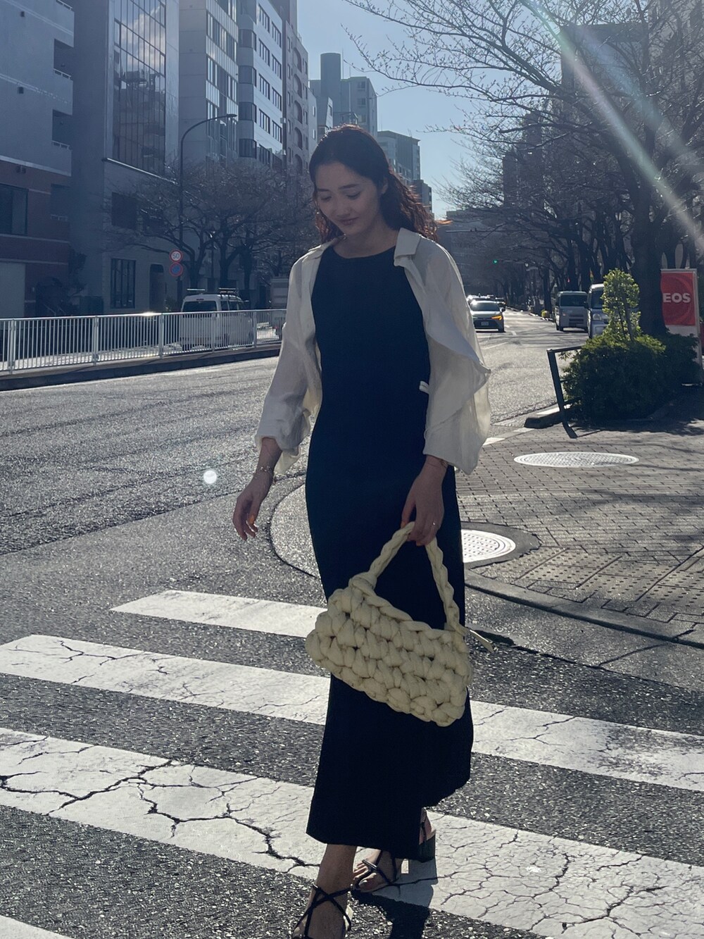 ブラック系のワンピース、ベージュ系のハンドバッグ、ブラック系のサンダルを着用したレディースの春コーディネートの6枚目の写真