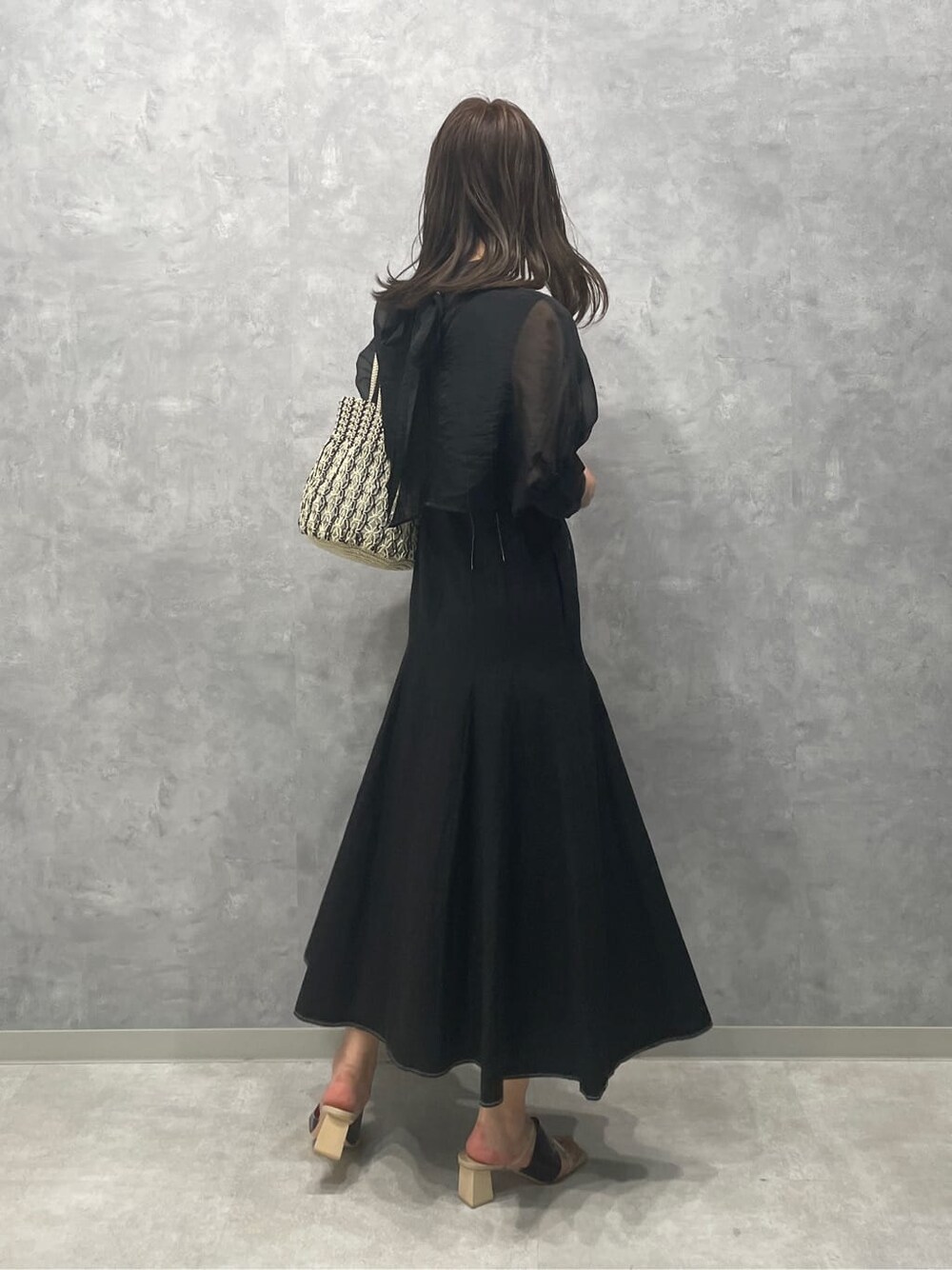 ブラウン系のサンダル、ホワイト系のハンドバッグ、ブラック系のワンピースを着用したレディースの夏コーディネートの3枚目の写真