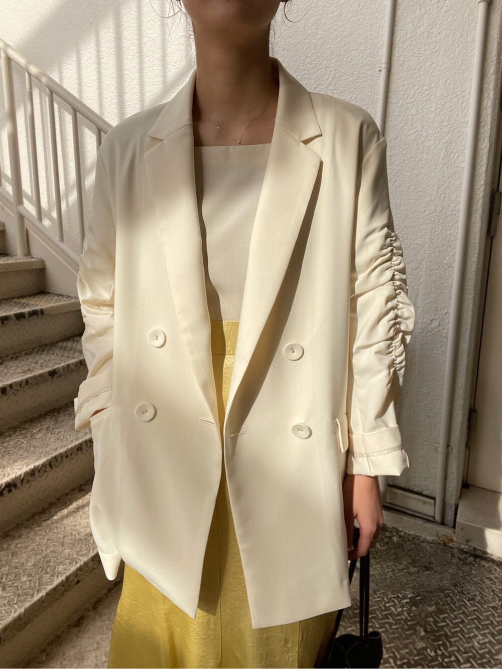 ホワイト系のシャツ/ブラウス、ホワイト系のテーラードジャケット、イエロー系のスカートを着用したレディースの冬コーディネートの3枚目の写真