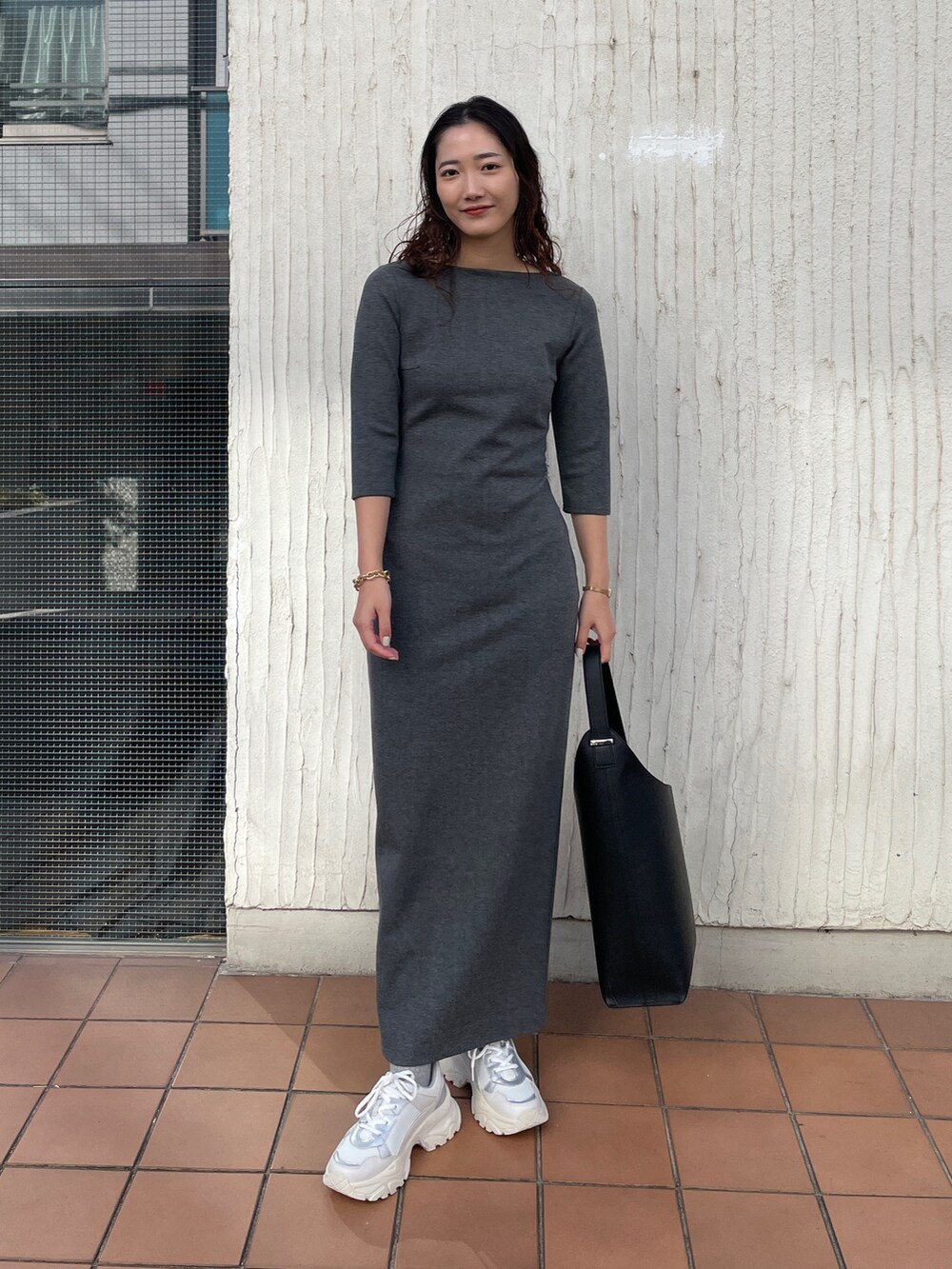 ブラック系のショルダーバッグ、グレー系のワンピース、ホワイト系のスニーカーを着用したレディースの冬コーディネートの3枚目の写真
