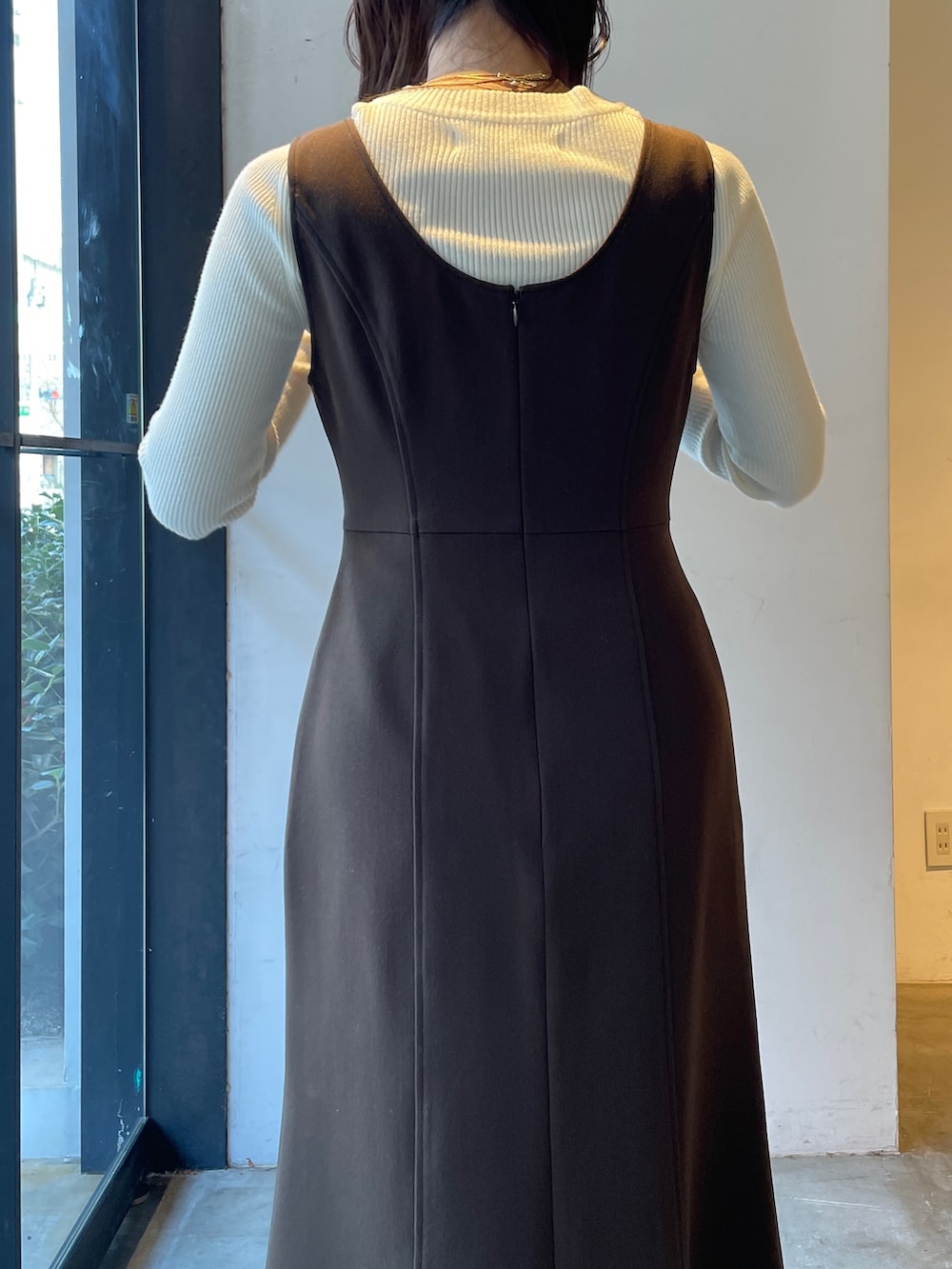 ブラック系のブーツ、ホワイト系のニット/セーター、ブラウン系のジャンパースカートを着用したレディースの冬コーディネートの7枚目の写真