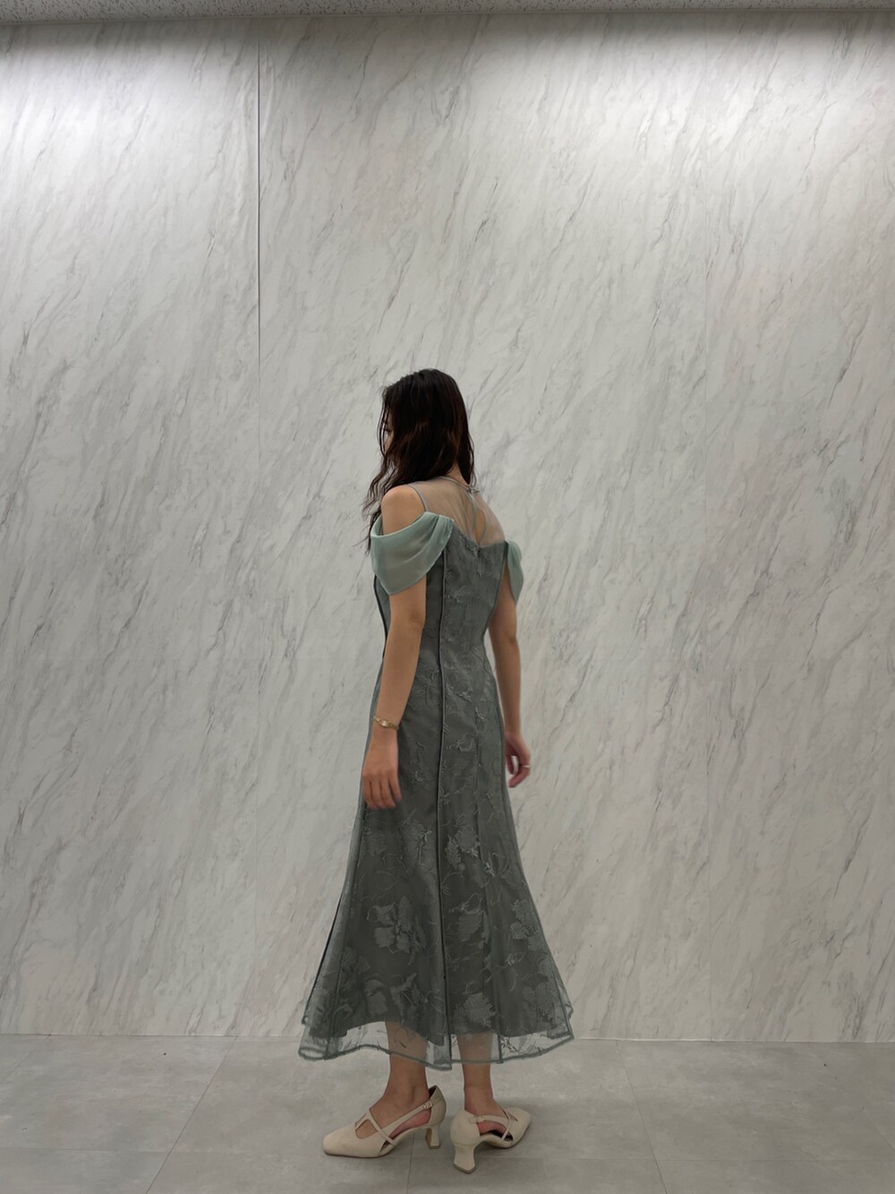 ホワイト系のパンプス、グリーン系のドレスを着用したレディースの冬コーディネートの3枚目の写真