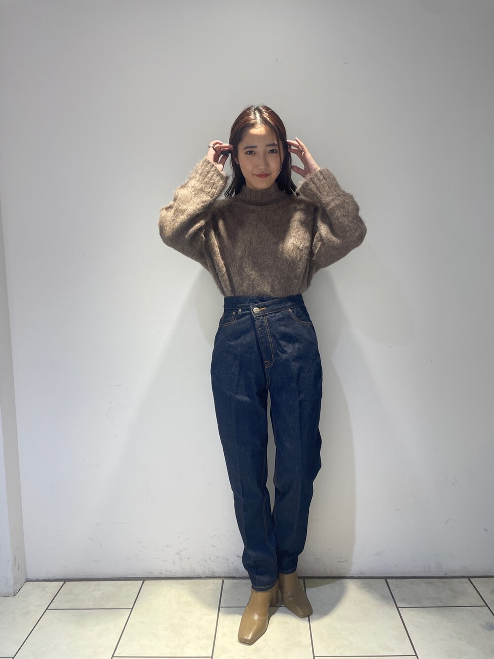 ブラウン系のニット/セーター、ベージュ系のブーツ、ブルー系のデニムパンツを着用したレディースの秋コーディネートの4枚目の写真