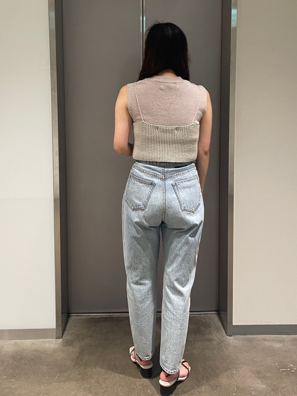 ブルー系のデニムパンツ、ベージュ系のニット/セーター、ブラック系のサンダルを着用したレディースの春コーディネートの5枚目の写真