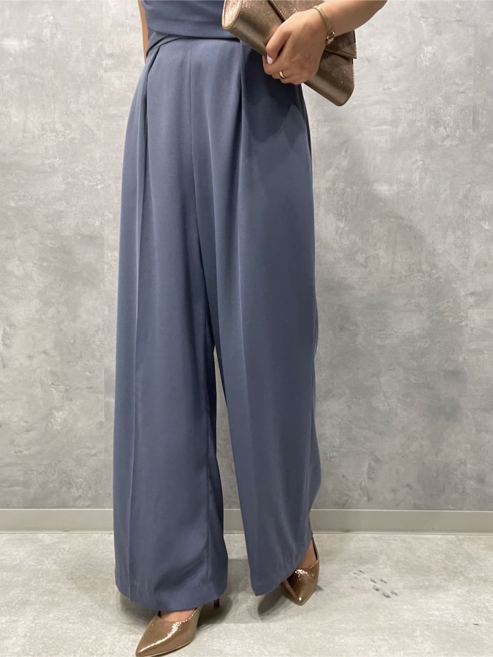 ゴールド系のパンプス、ゴールド系のクラッチバッグ、ブルー系のパンツドレスを着用したレディースの夏コーディネートの10枚目の写真