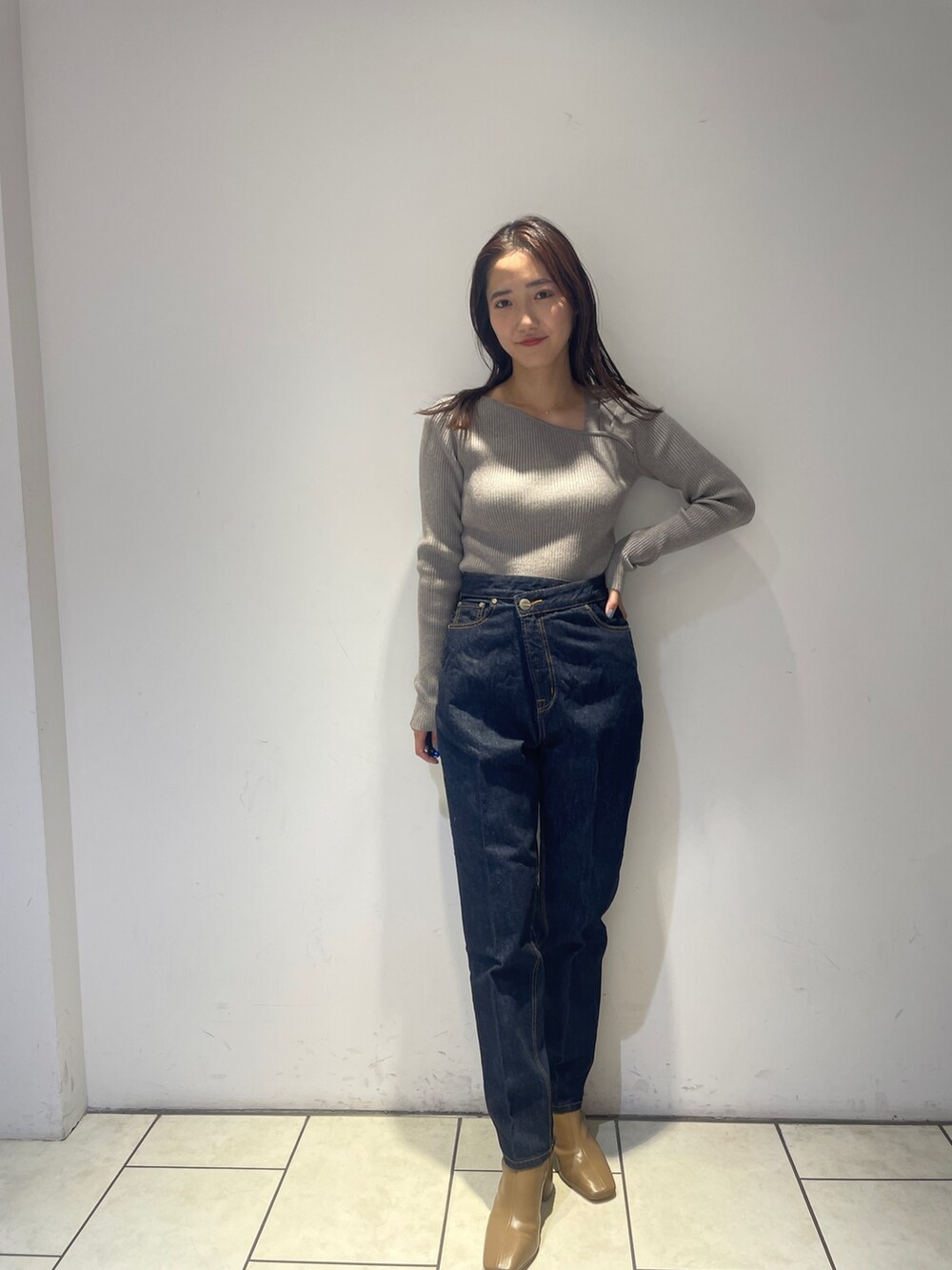 ホワイト系のノーカラーコート、グレー系のニット/セーター、ブルー系のデニムパンツを着用したレディースの秋コーディネートの4枚目の写真