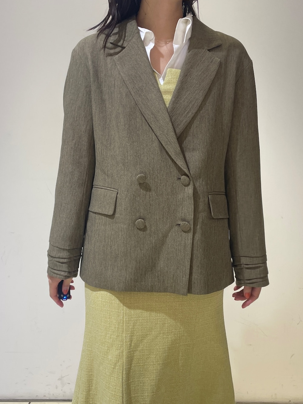 イエロー系のワンピース、ホワイト系のブーツ、ブラウン系のテーラードジャケットを着用したレディースの秋コーディネートの6枚目の写真