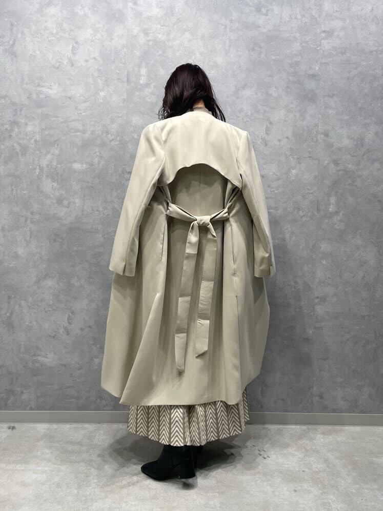 ホワイト系のノーカラーコート、ブラック系のブーツ、ベージュ系のワンピースを着用したレディースの秋コーディネートの10枚目の写真