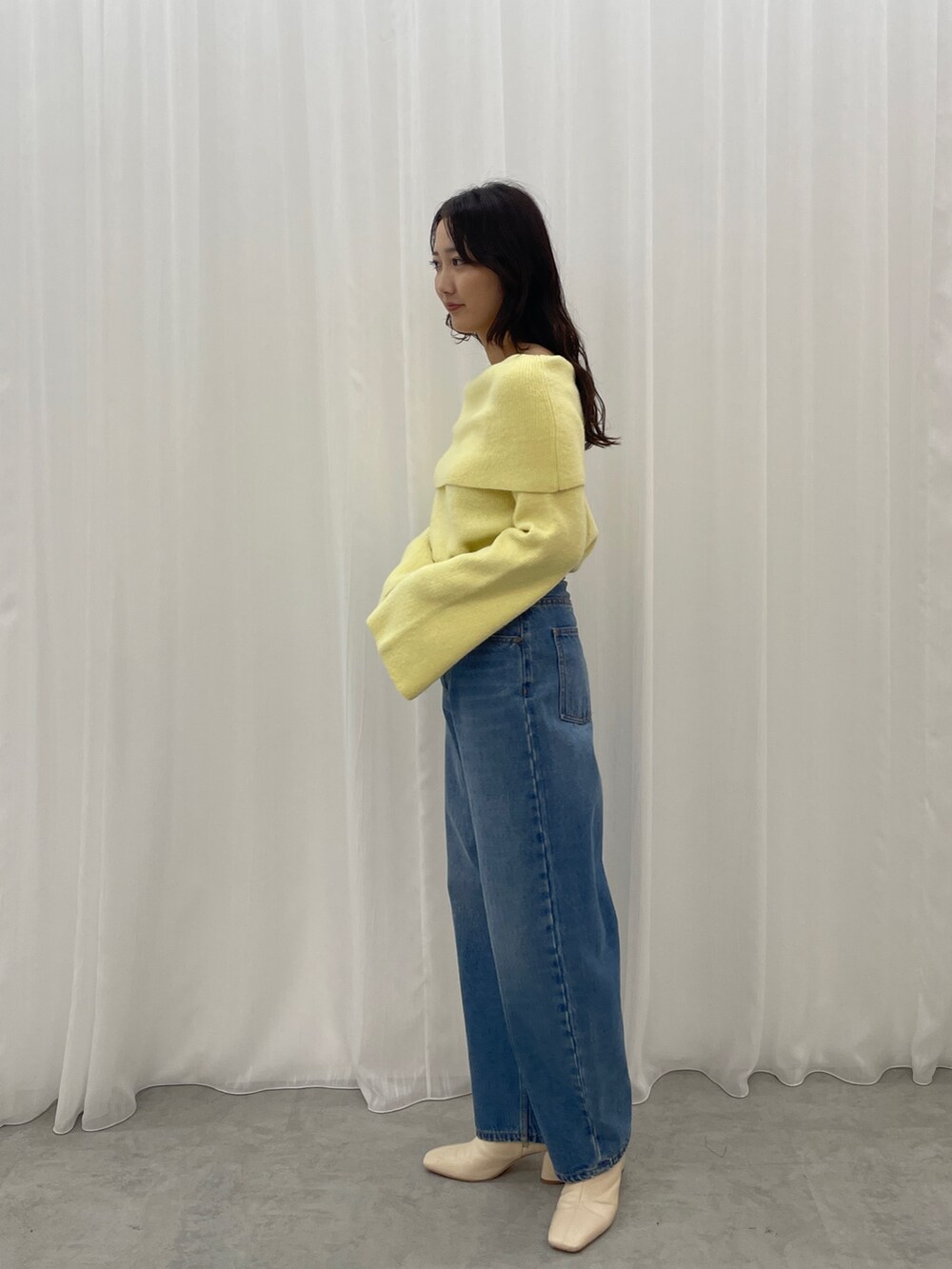 ブルー系のデニムパンツ、ホワイト系のブーツ、イエロー系のニット/セーターを着用したレディースの秋コーディネートの4枚目の写真