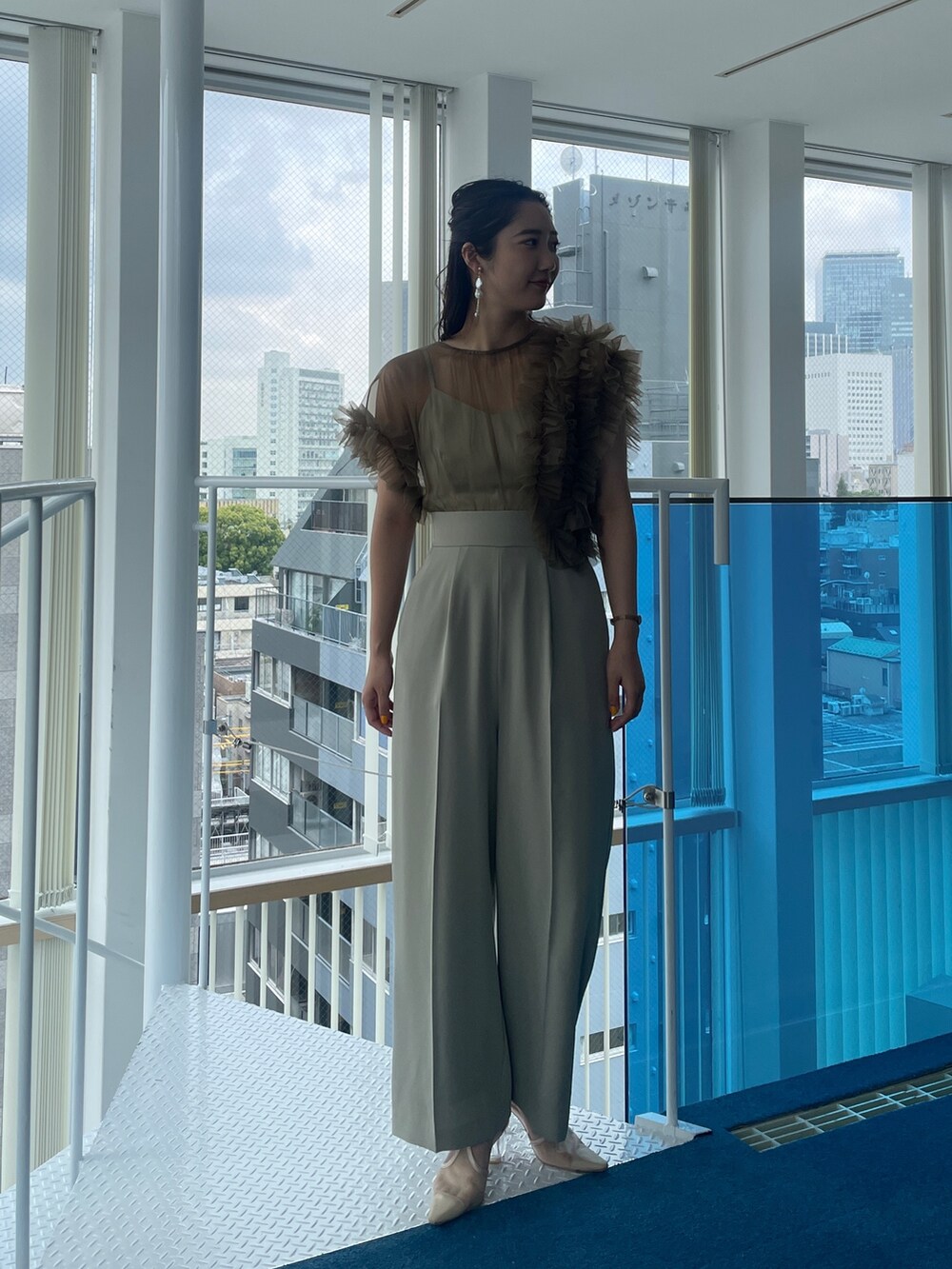 グリーン系のパンツドレス、ベージュ系のパンプスを着用したレディースの春コーディネートの3枚目の写真