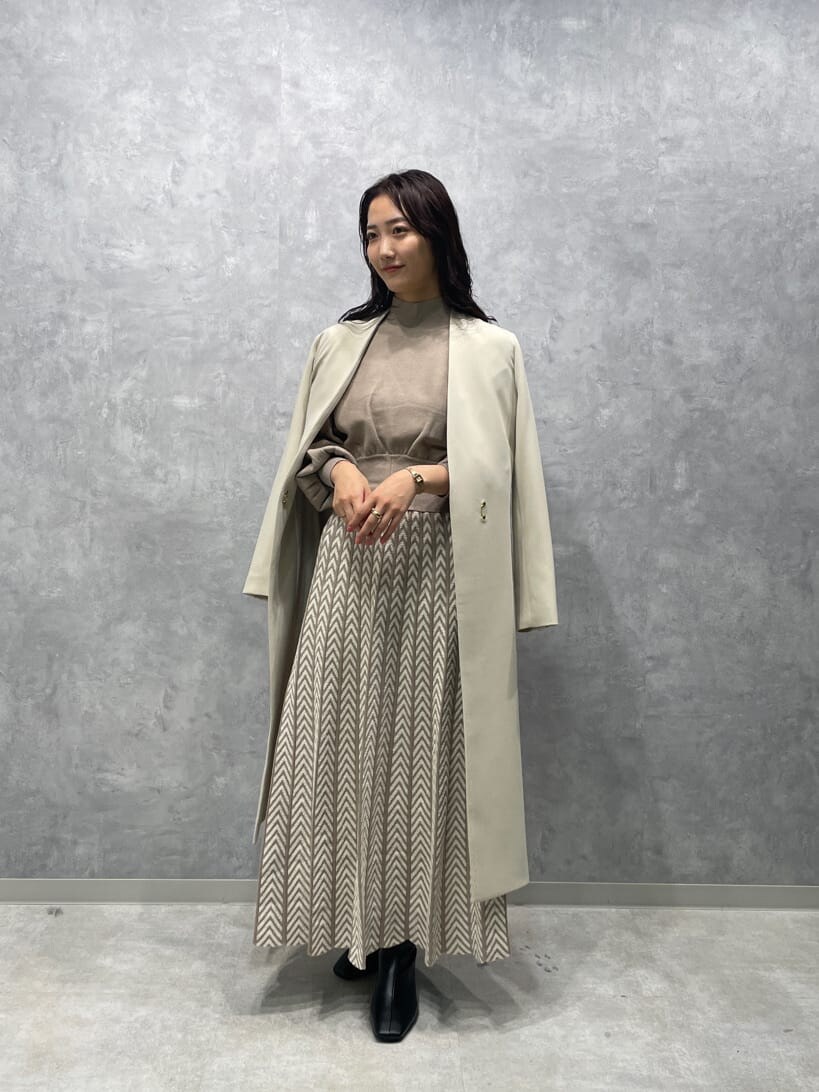 ホワイト系のノーカラーコート、ブラック系のブーツ、ベージュ系のワンピースを着用したレディースの秋コーディネートの2枚目の写真