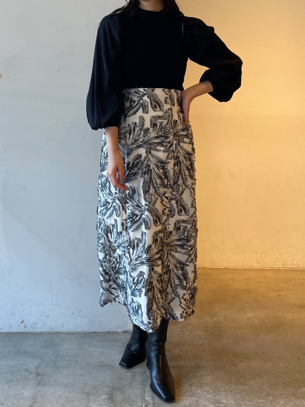 ブラック系のスカート、ブラック系のニット/セーター、ブラック系のブーツを着用したレディースの冬コーディネートの2枚目の写真