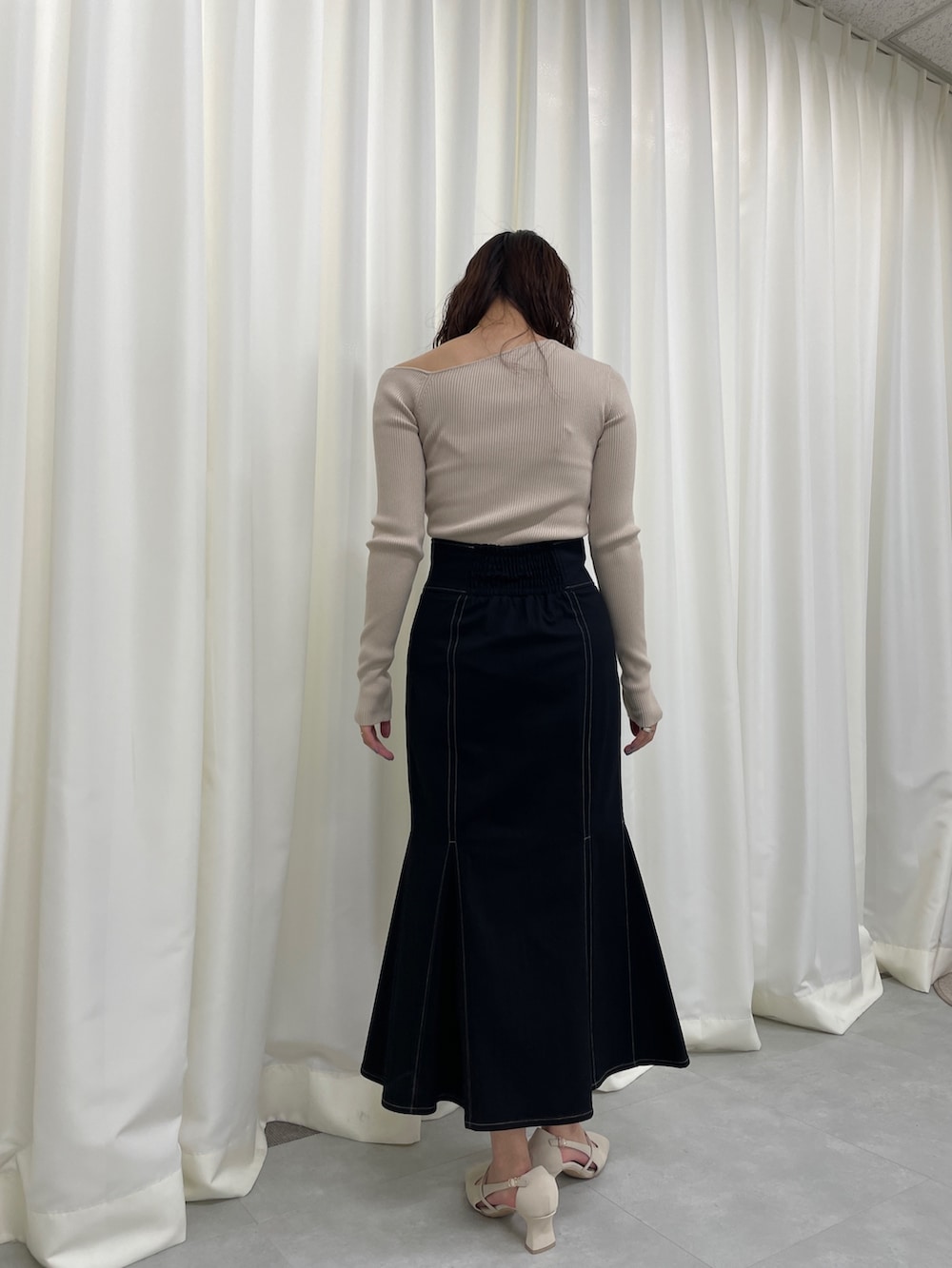 ブラック系のスカート、ベージュ系のニット/セーター、ホワイト系のパンプスを着用したレディースの冬コーディネートの6枚目の写真