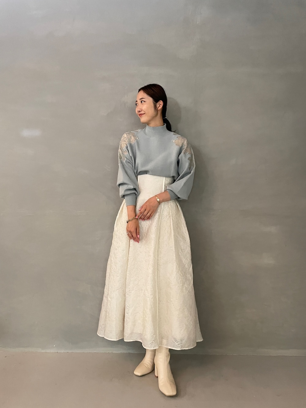グレー系のニット/セーター、ホワイト系のスカート、ホワイト系のブーツを着用したレディースの夏コーディネートの2枚目の写真