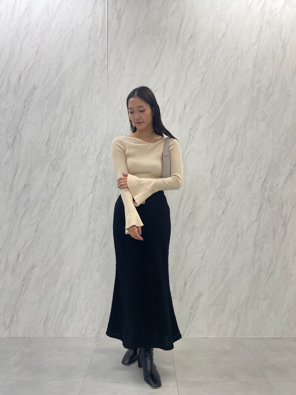 ブラック系のブーツ、ホワイト系のハンドバッグ、ブラック系のスカートを着用したレディースの秋コーディネートの7枚目の写真