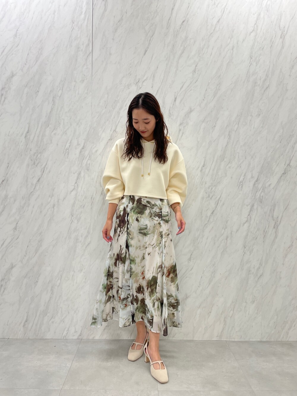 ホワイト系のパンプス、ベージュ系のスカート、ホワイト系のパーカーを着用したレディースの冬コーディネートの4枚目の写真