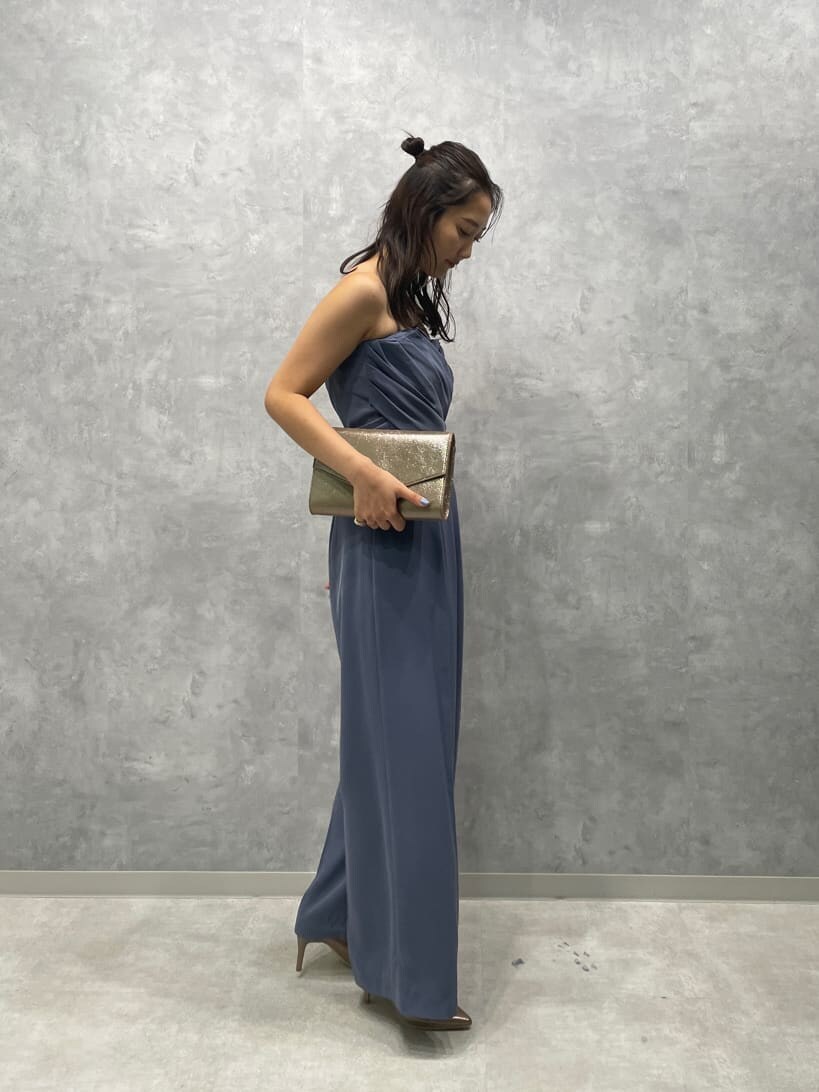 ゴールド系のパンプス、ゴールド系のクラッチバッグ、ブルー系のパンツドレスを着用したレディースの夏コーディネートの5枚目の写真
