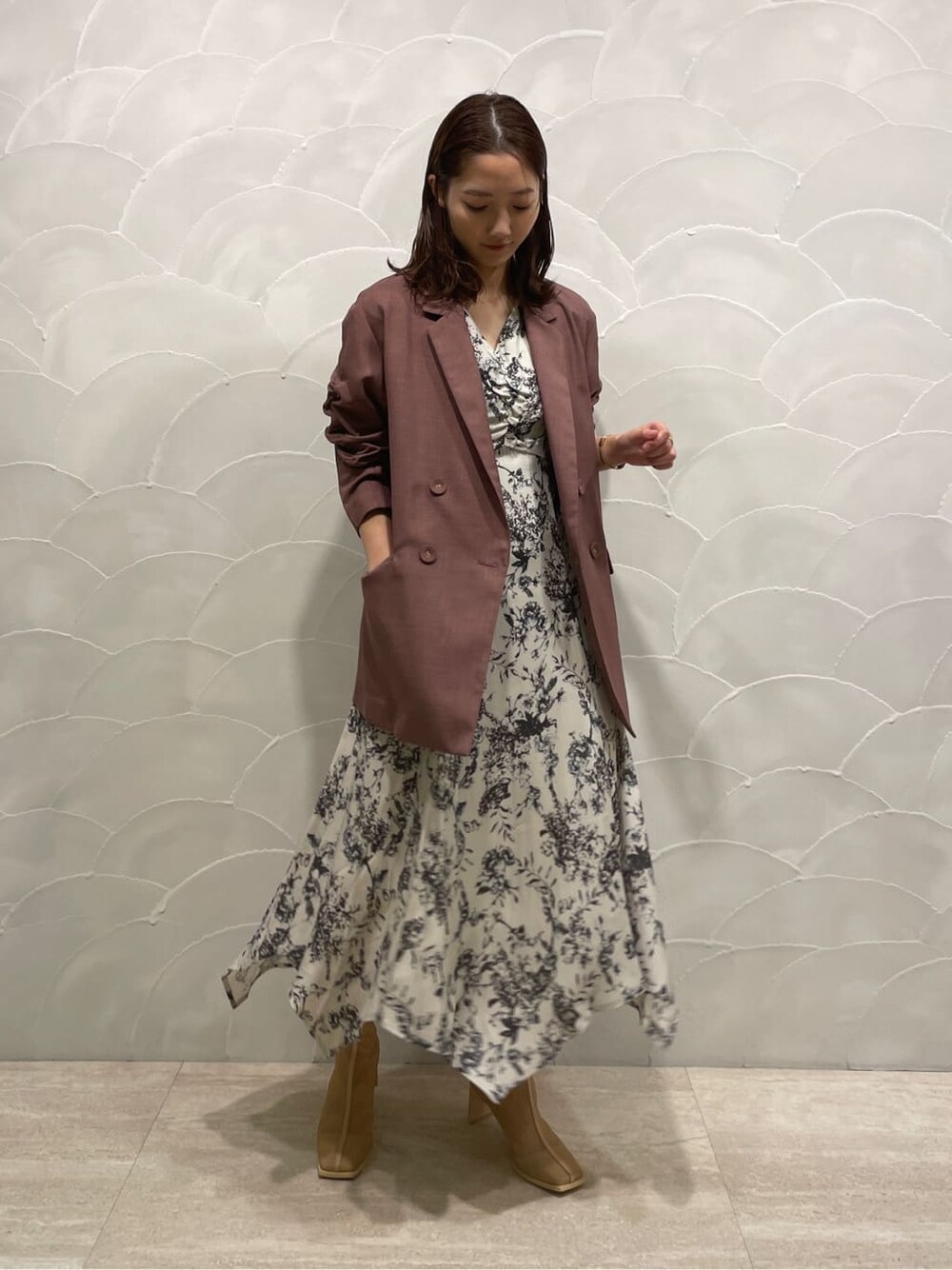 パープル系のテーラードジャケット、ベージュ系のブーツ、グレー系のワンピースを着用したレディースの春コーディネートの2枚目の写真