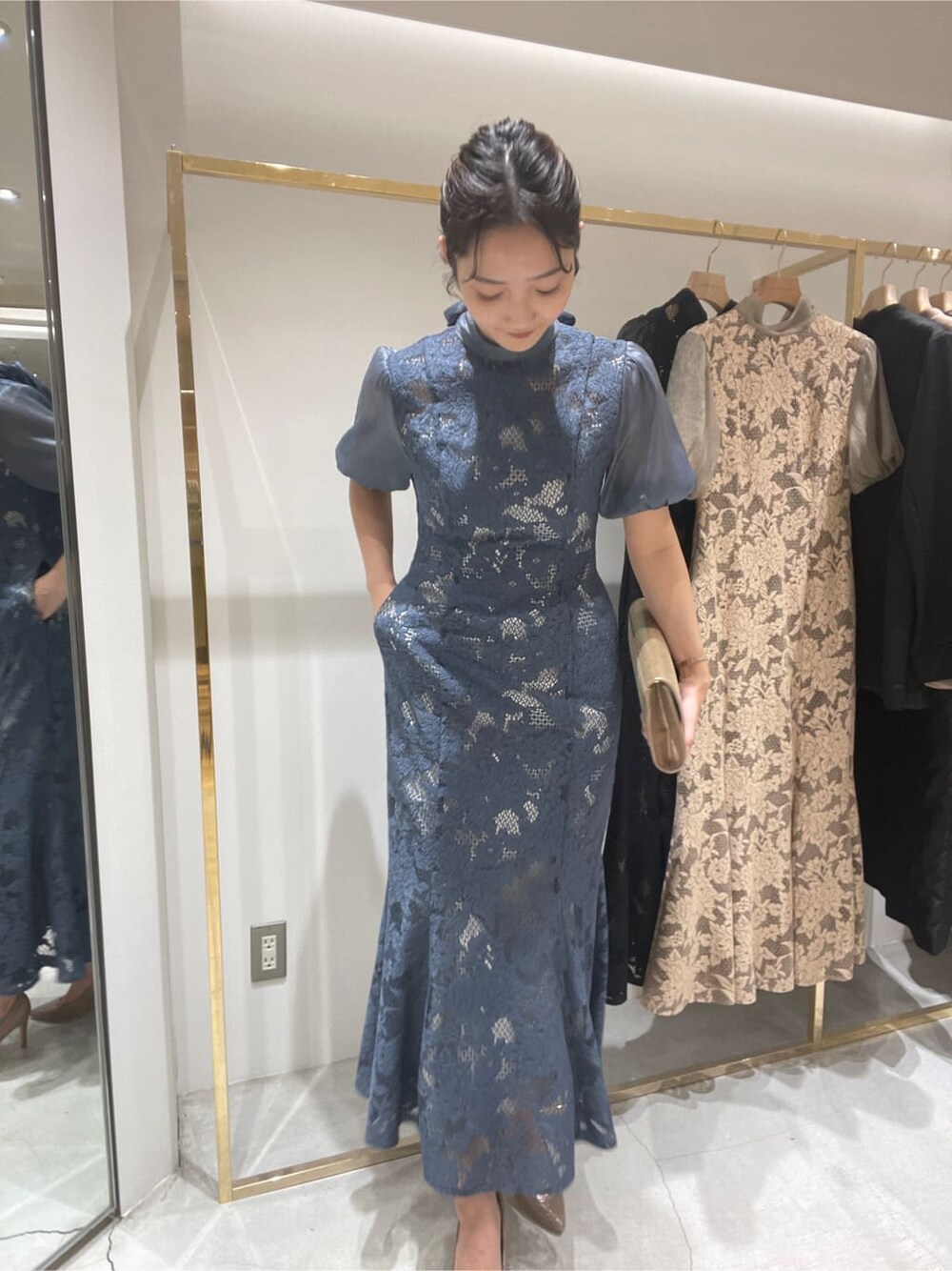 ゴールド系のクラッチバッグ、ブルー系のドレスを着用したレディースの春コーディネートの2枚目の写真