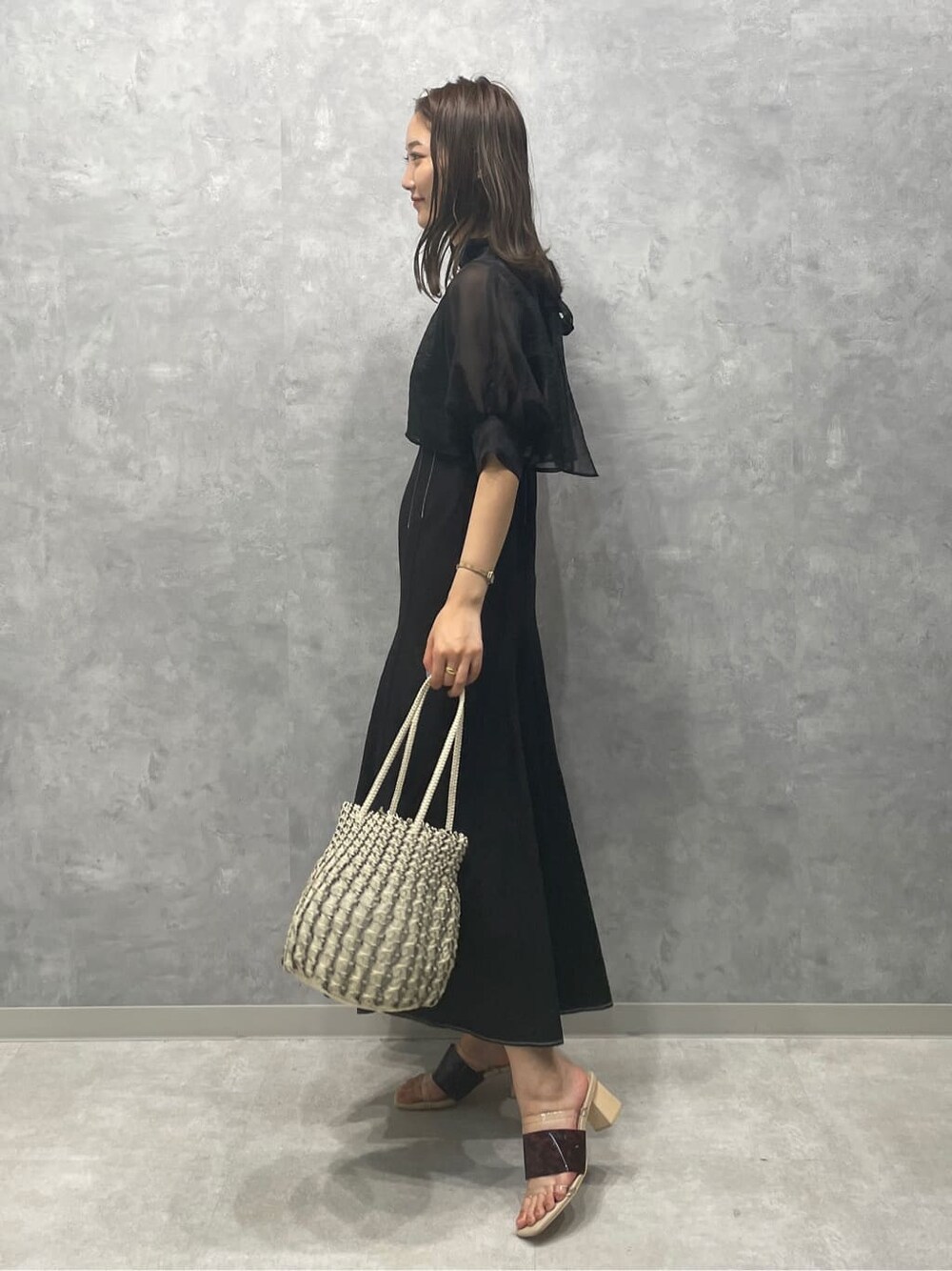 ブラウン系のサンダル、ホワイト系のハンドバッグ、ブラック系のワンピースを着用したレディースの夏コーディネートの2枚目の写真