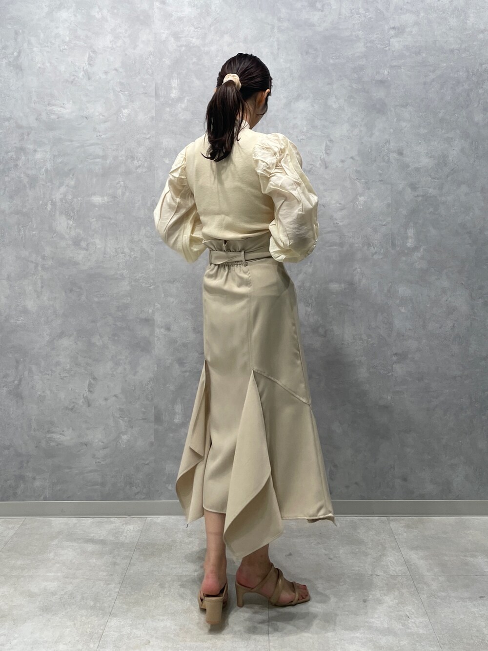 ベージュ系のサンダル、ホワイト系のニット/セーター、ホワイト系のスカートを着用したレディースの冬コーディネートの5枚目の写真